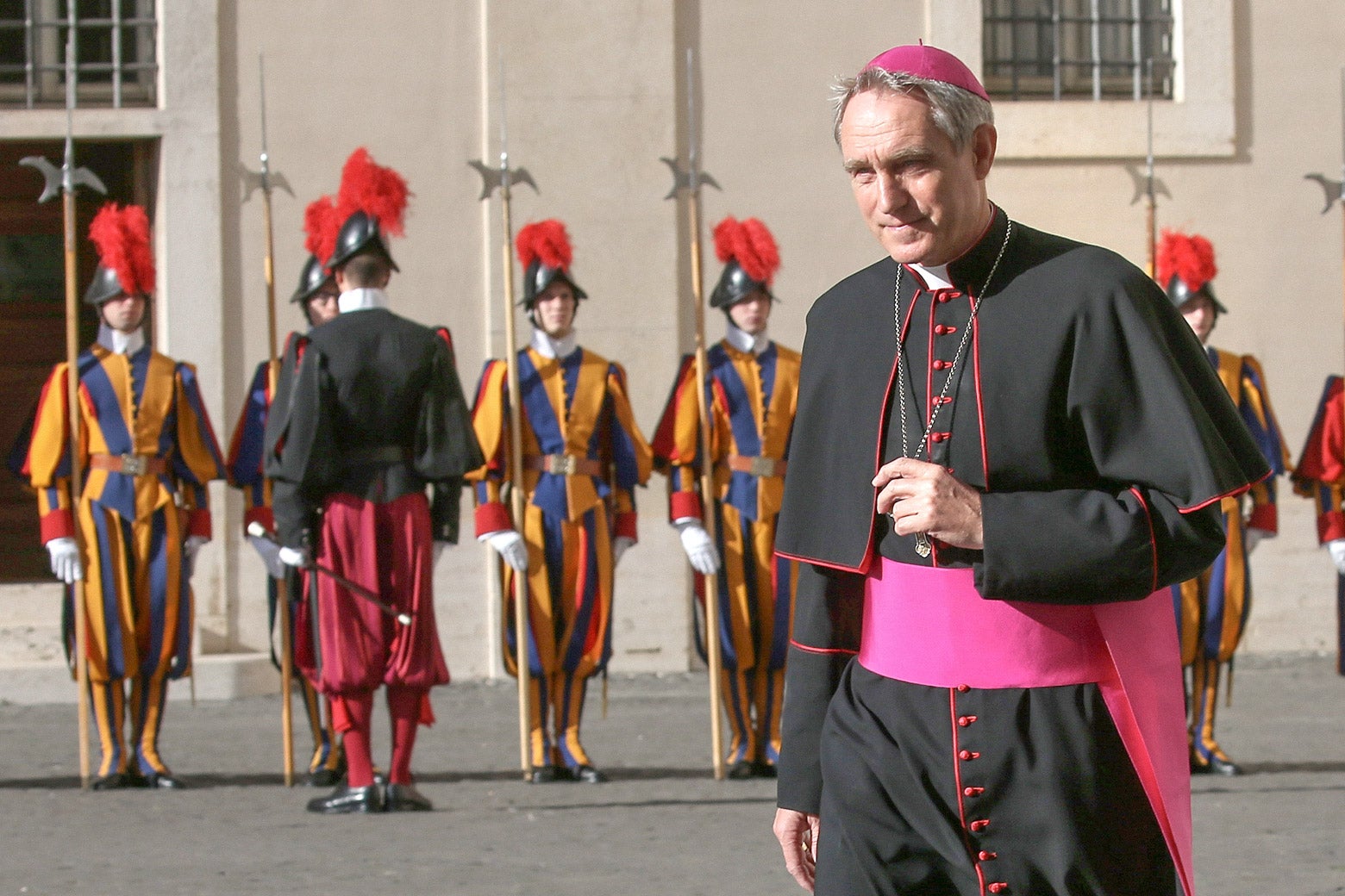 A man in papal garments, in front of guards in Vatican City.