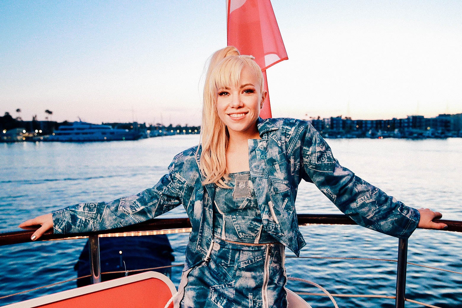 Carly Rae Jepsen in an all-denim outfit on a boat in a harbor.