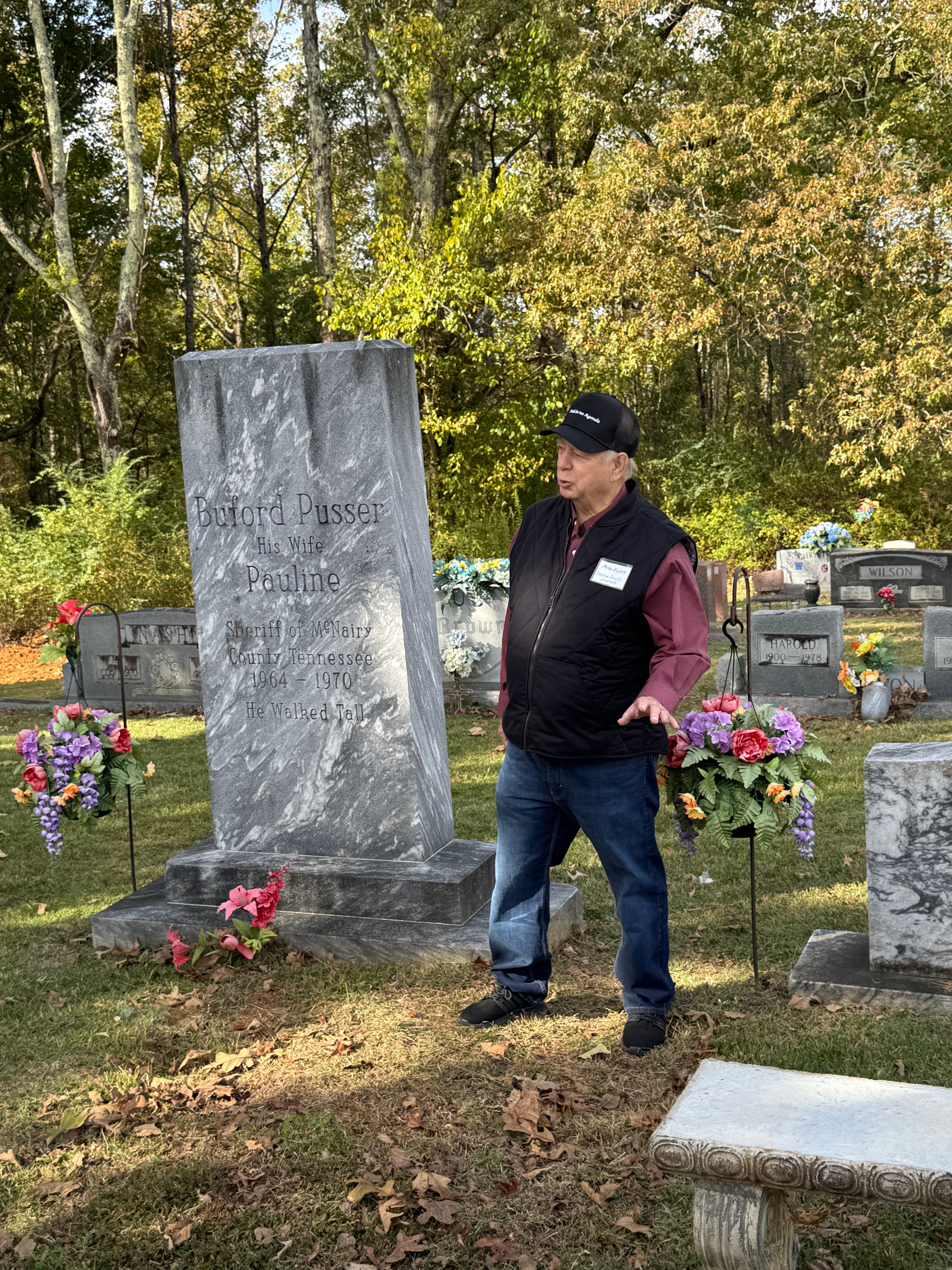 A man standing at a gravesite in the fall.