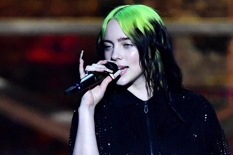 Billie Eilish sings, holding a mic to her mouth