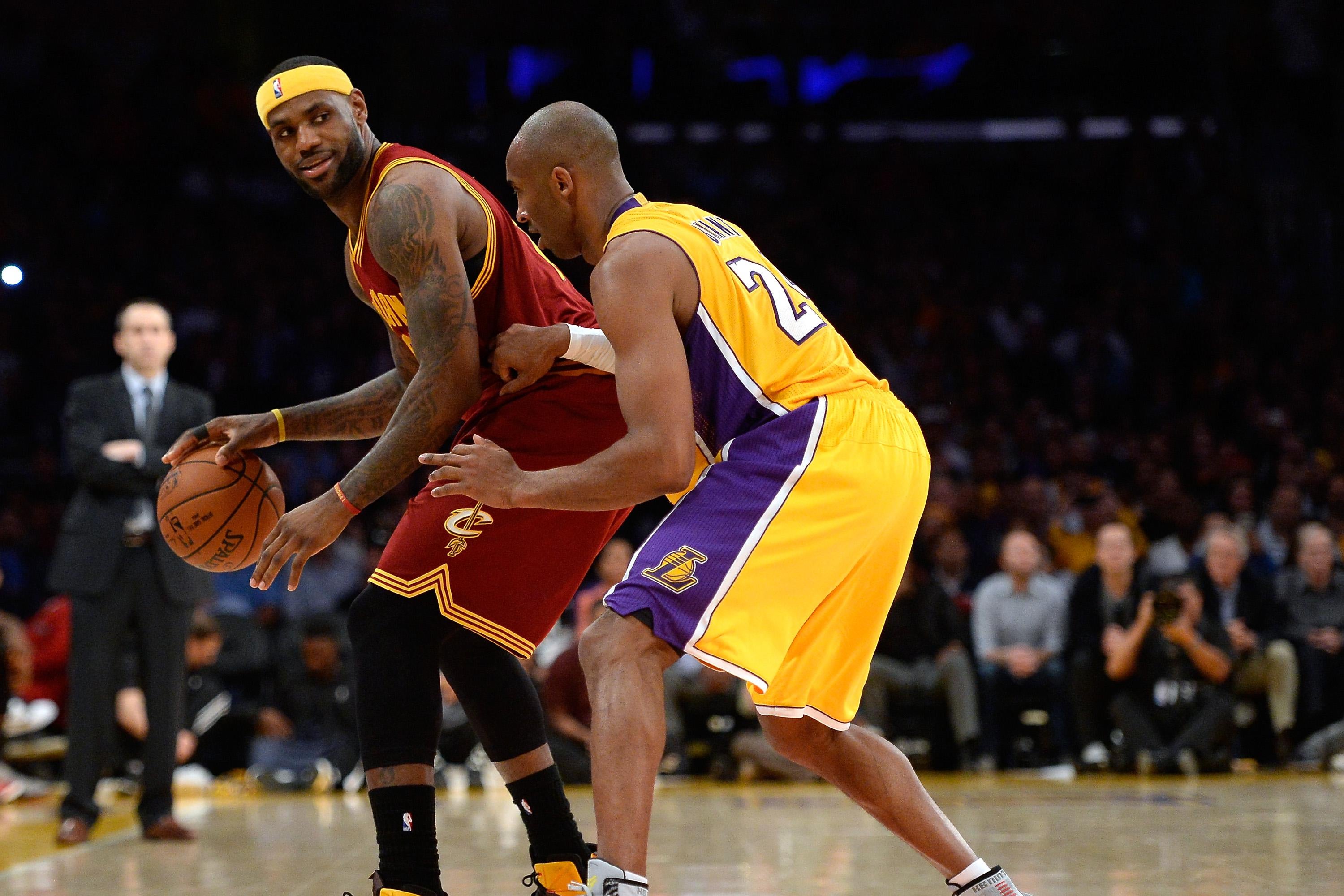 LeBron James of the Cleveland Cavaliers dribbles as he is guarded by Kobe Bryant.