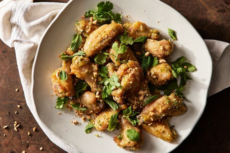 Plate of golden fish sauce wings topped with mint, cilantro, and chopped peanuts