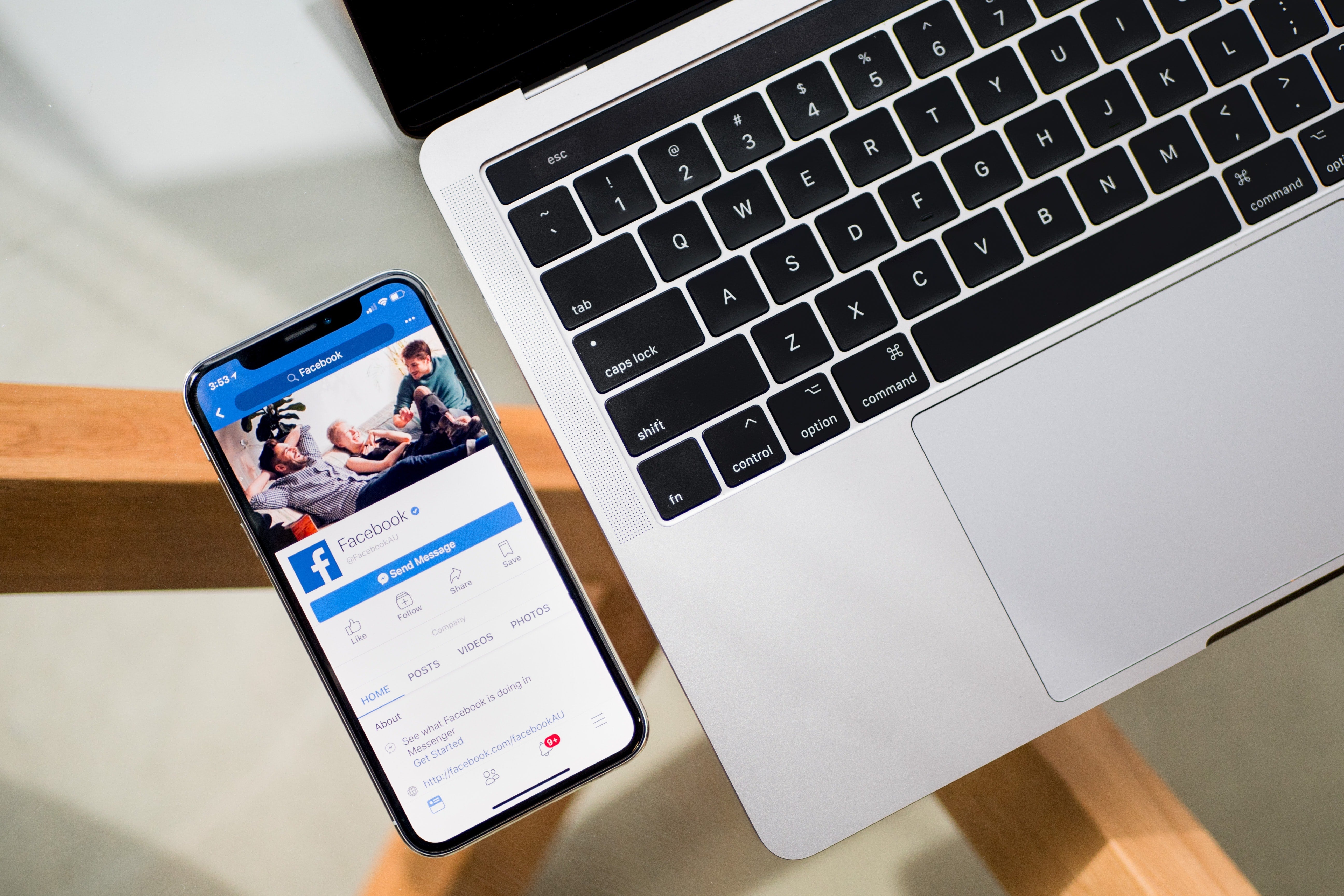 Facebook is on an iPhone X screen, which sits near a MacBook keyboard.