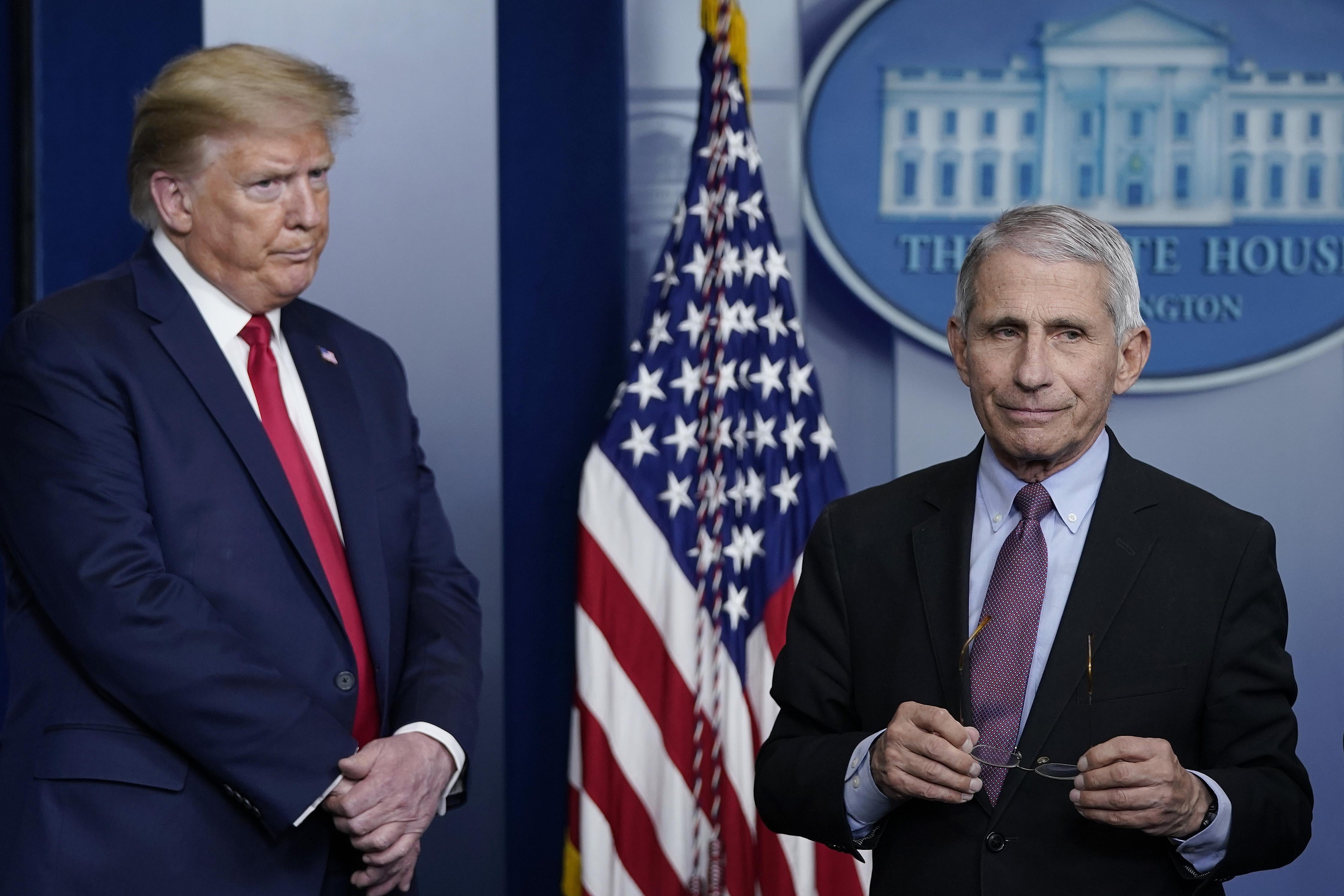 Trump, with furrowed brow, on the left, and Fauci holding his glasses, looking off to the side, on the right.