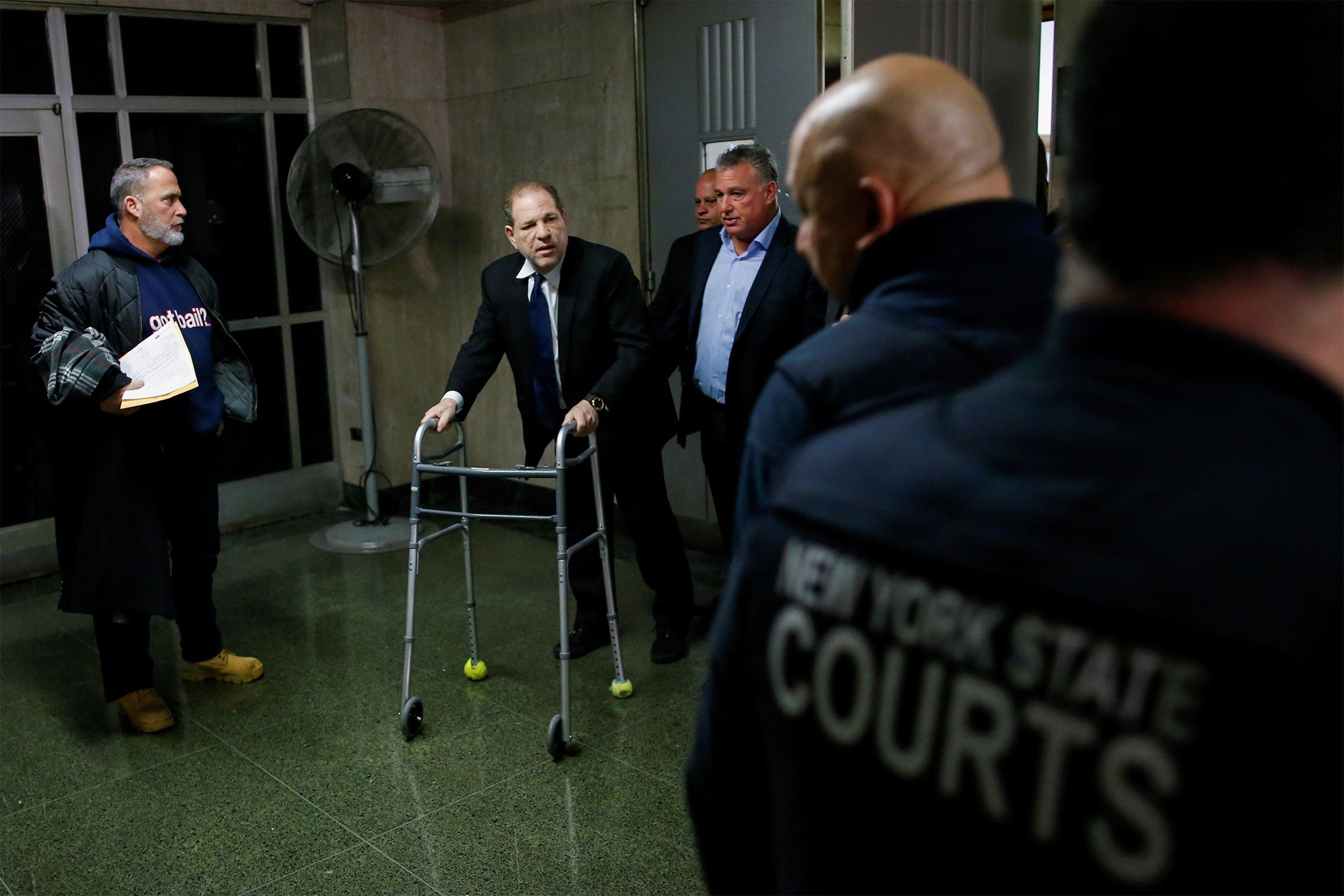 Weinstein, aided by a walker, exits a courtroom at the New York Supreme Court.