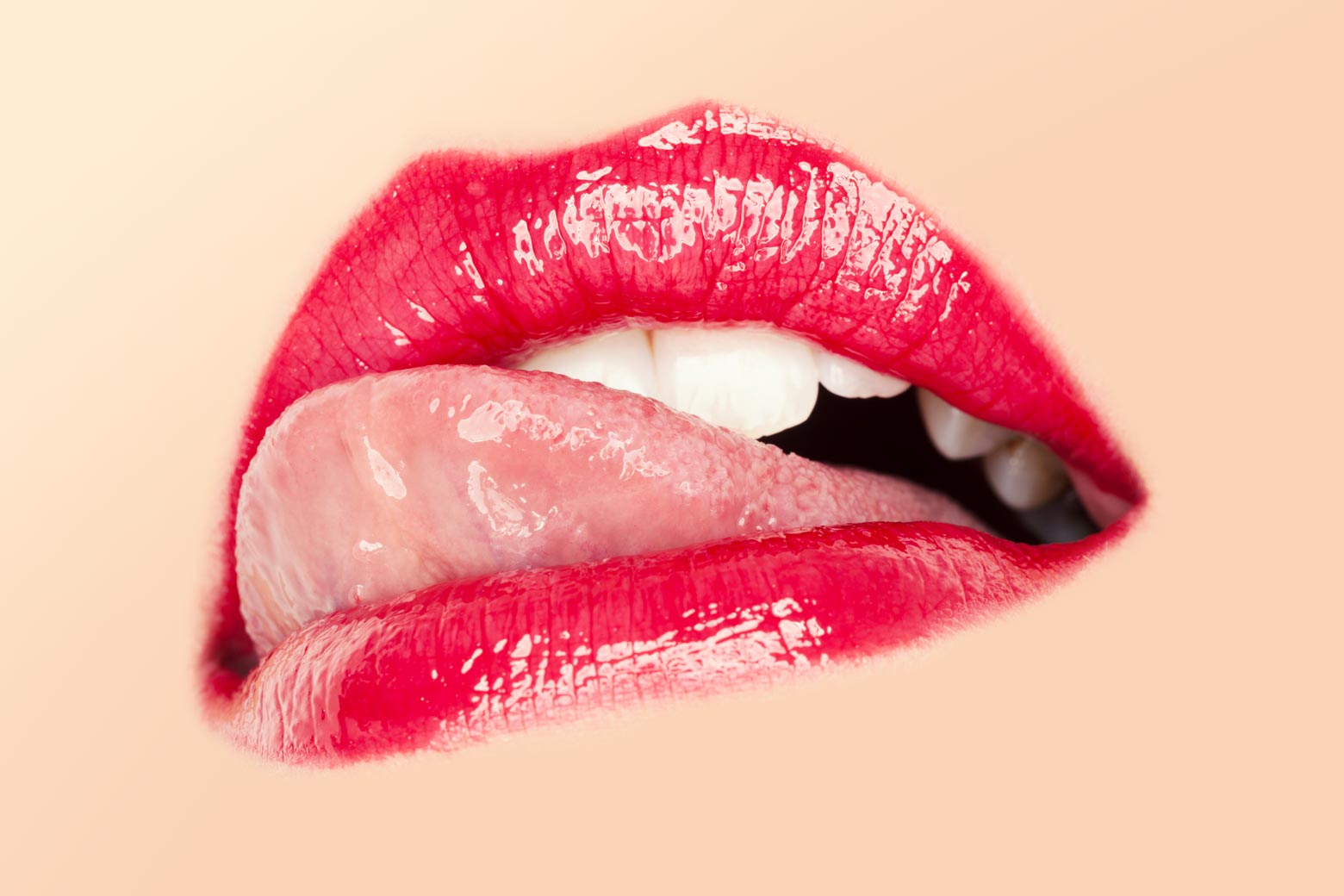 Close-up on the mouth of a woman licking her red glossy lips