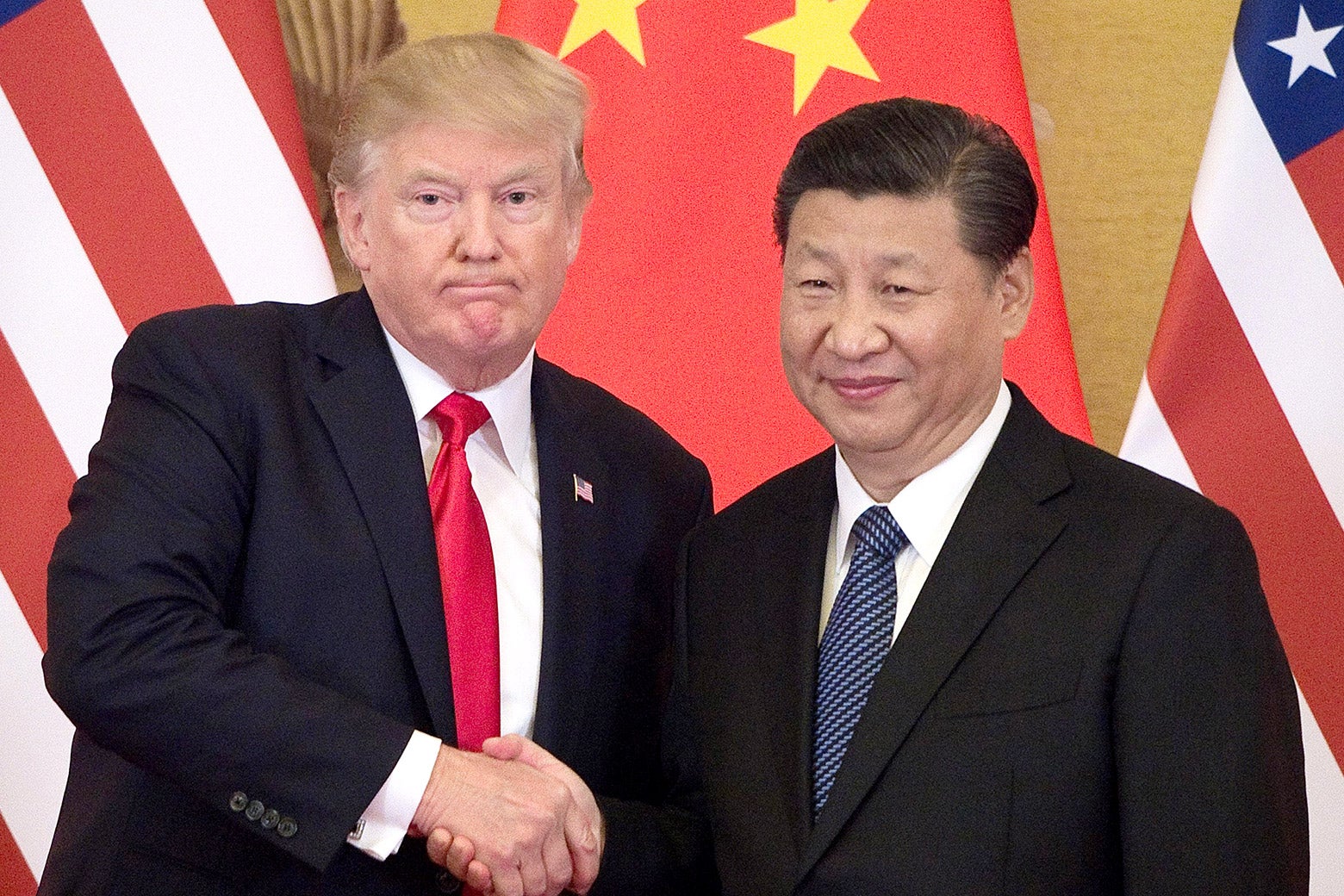 Donald Trump and Xi Jinping, standing, shake hands.