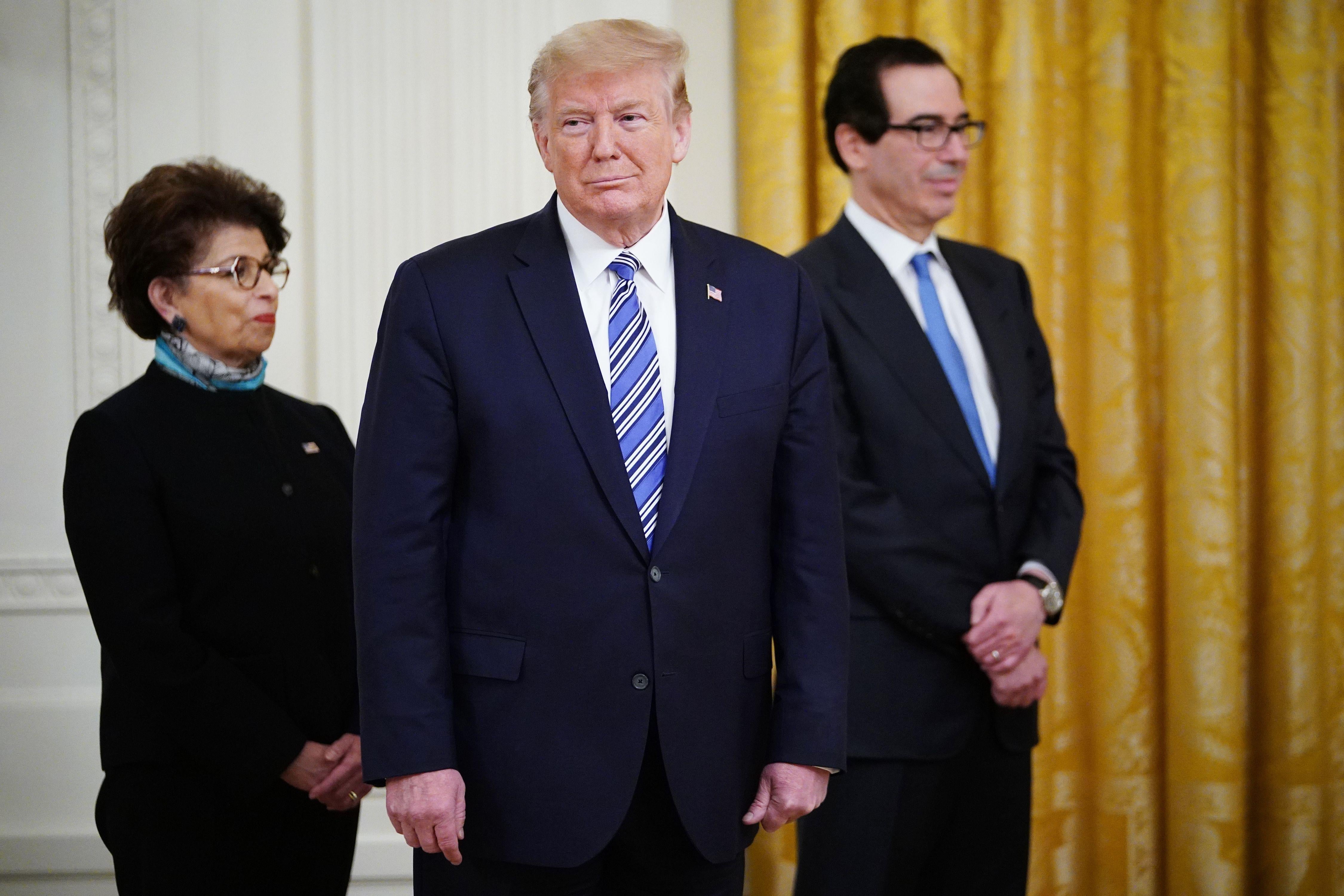 Donald Trump stands in front of Jovita Carranza and Steven Mnuchin.