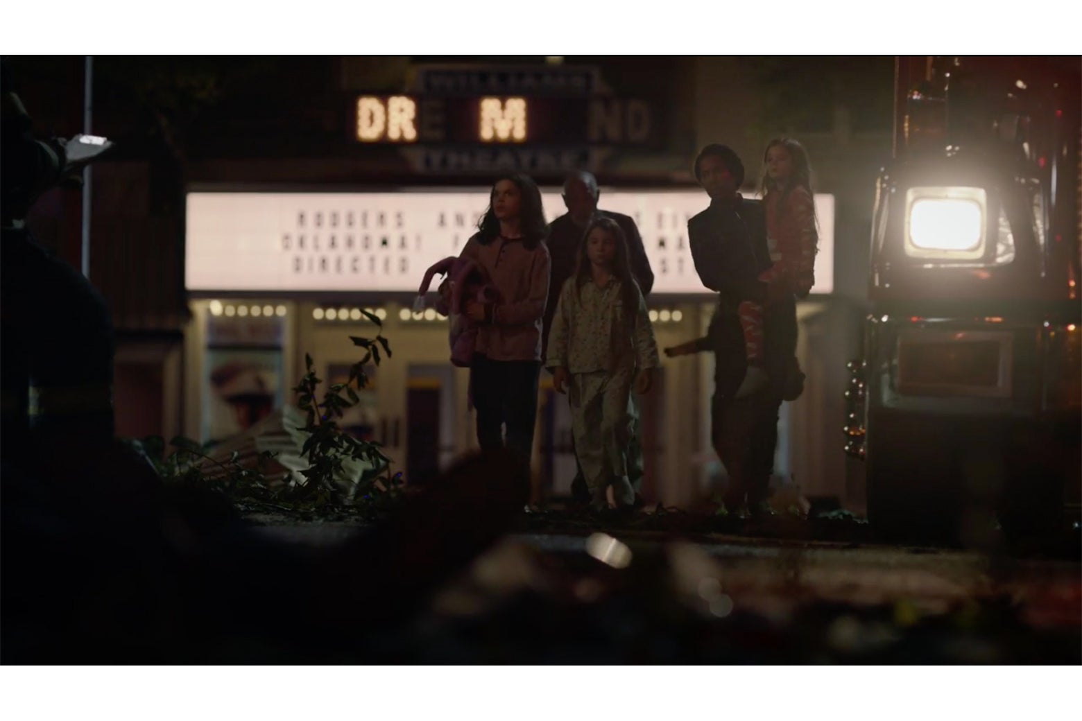 Angela Abar and her family exit Tulsa's Dreamland Theater. The sign has been smashed by falling squid, leaving only the letters D R M illuminated.
