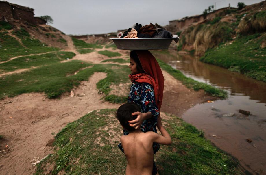 An Afghan refugee girl carries her laundry on her head after washing it in a polluted stream on World Water Day in a poor neighborhood on the outskirts of Islamabad, Pakistan on March 22, 2013. 