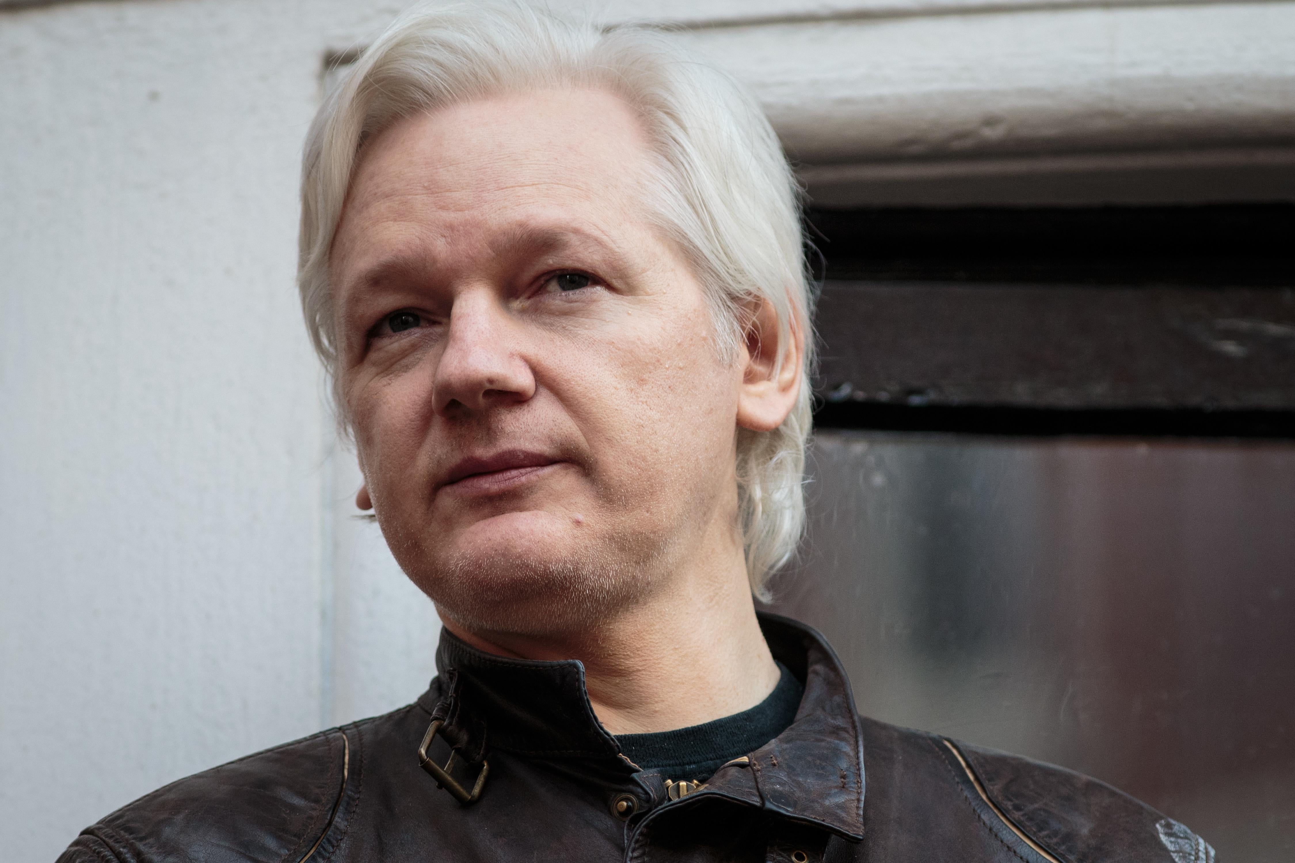 Julian Assange looks out from a balcony.