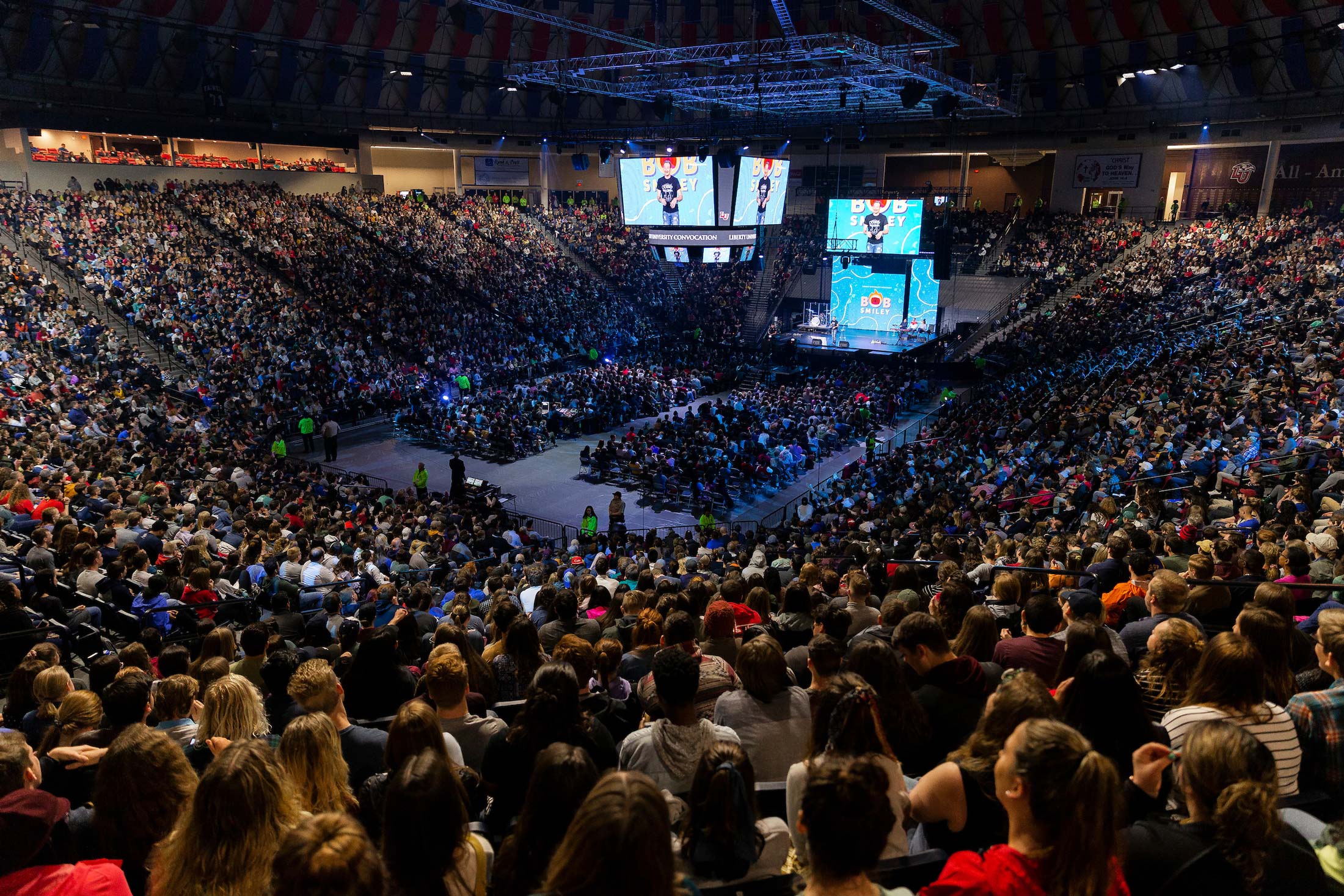 A huge arena filled with Liberty University students. Bob Smiley can be seen on the stage and on large screens in the center of the space.