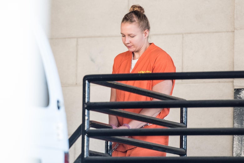 Reality Winner walks down stairs outside the courthouse wearing an orange prison jumpsuit and handcuffs