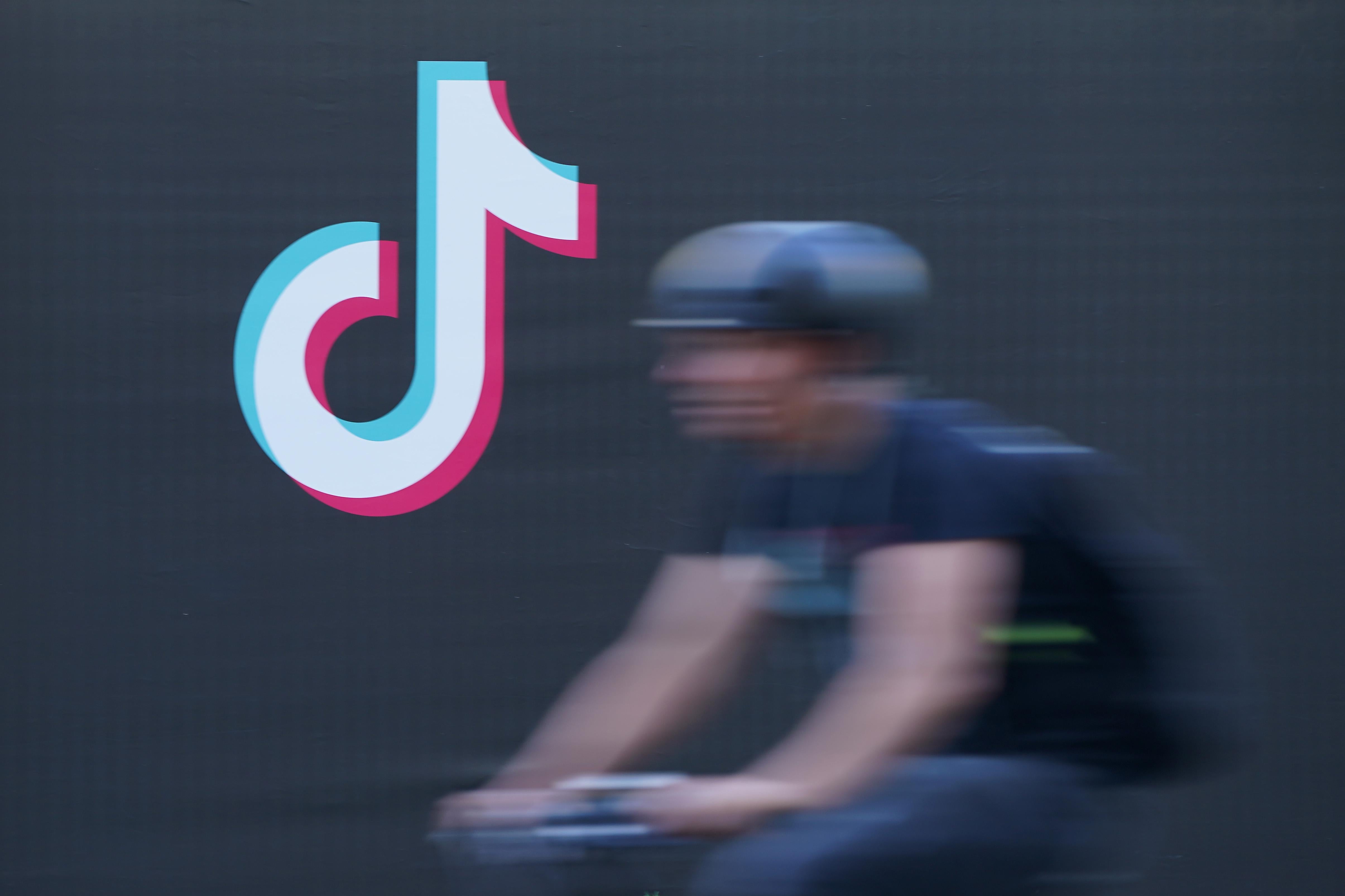 A blurred bicyclist rides past a TikTok advertisement.