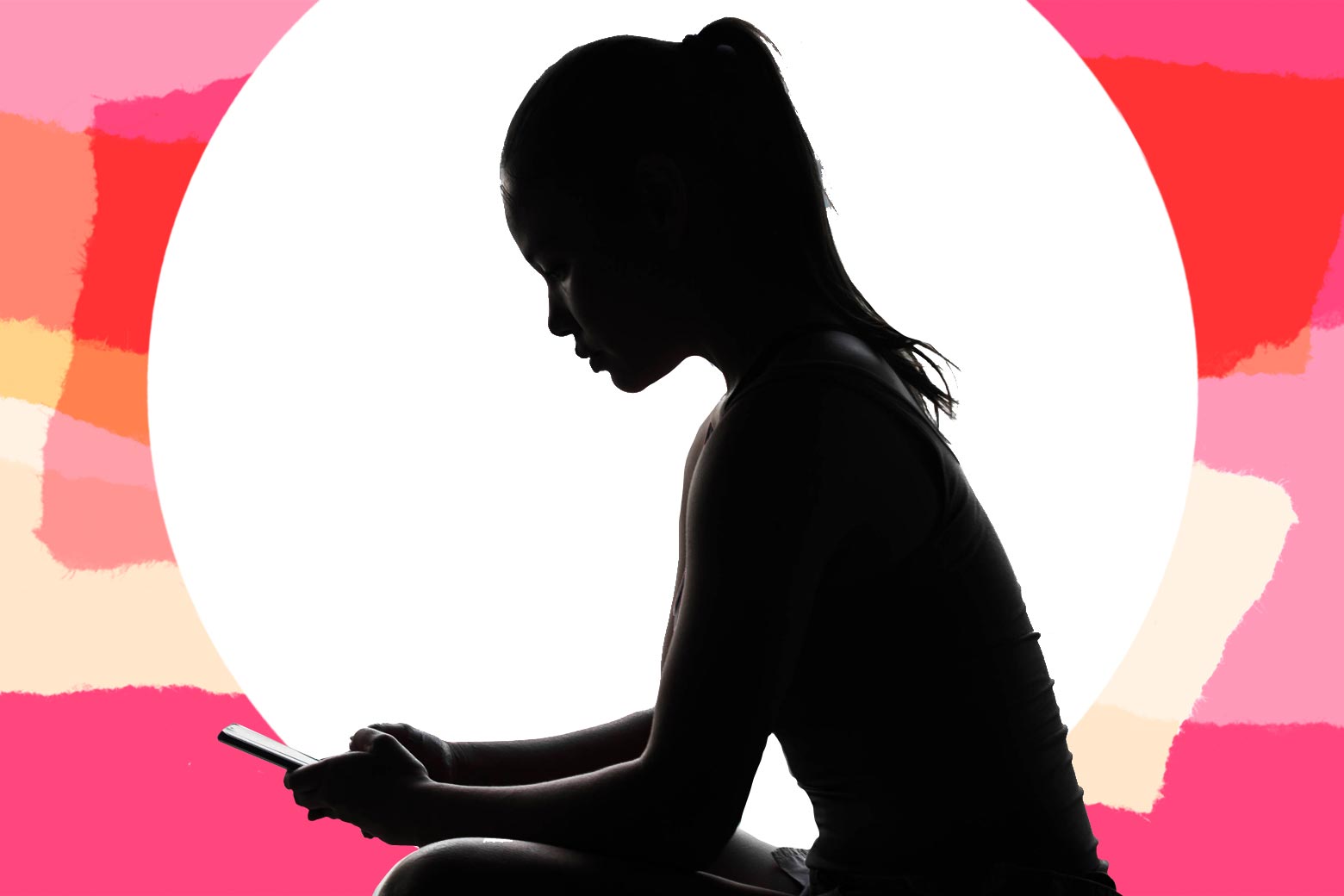 A woman in silhouette looking at her phone.