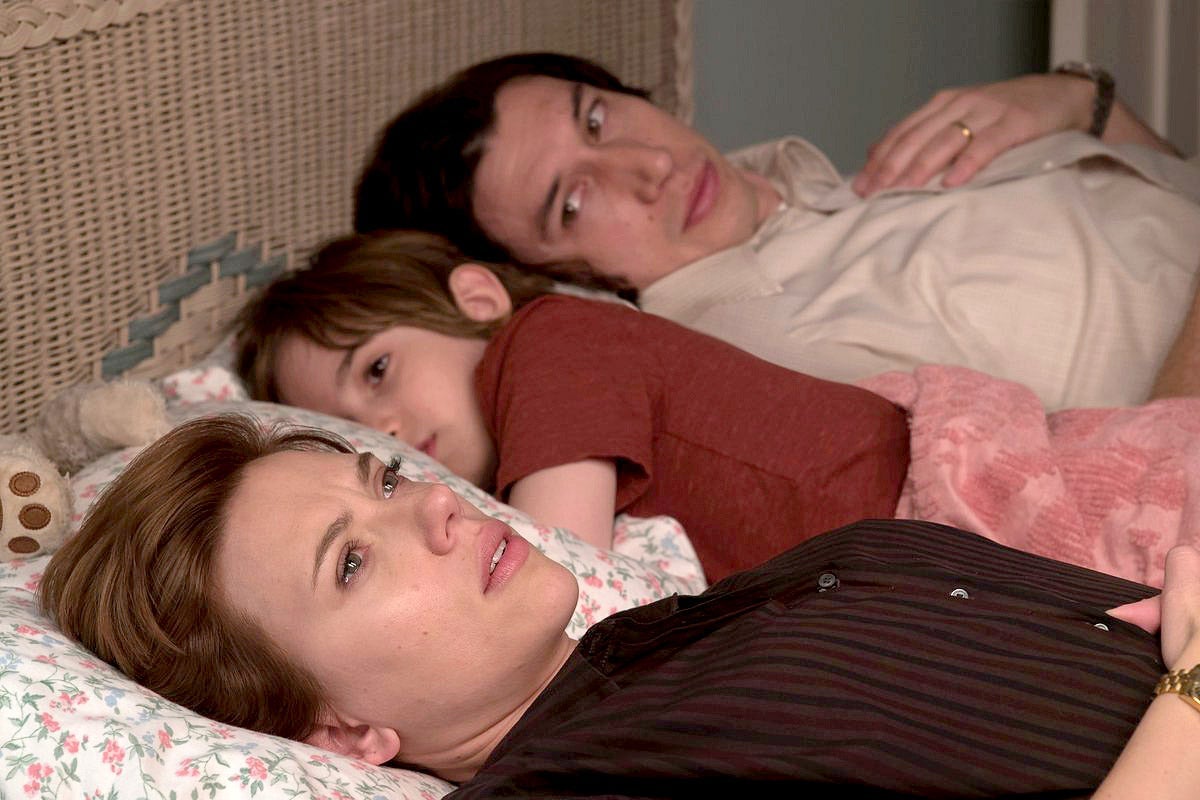 Scarlett Johansson, Azhy Robertson, and Adam Driver lie in bed in this still from Marriage Story.