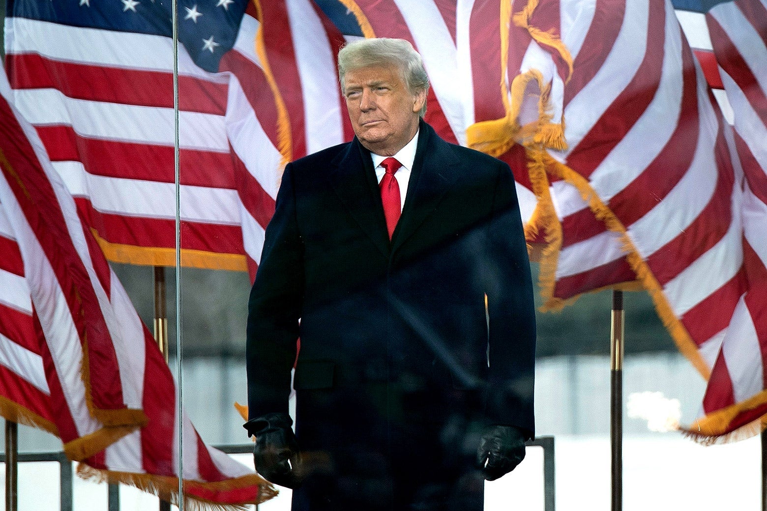 Donald Trump in front of the White House and several U.S. flags.