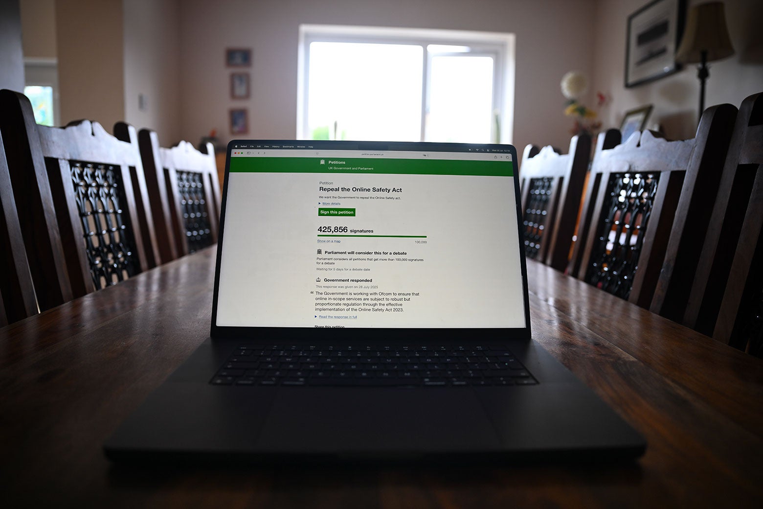 A tablet sits on the conference table in a dark and stodgy British meeting room.