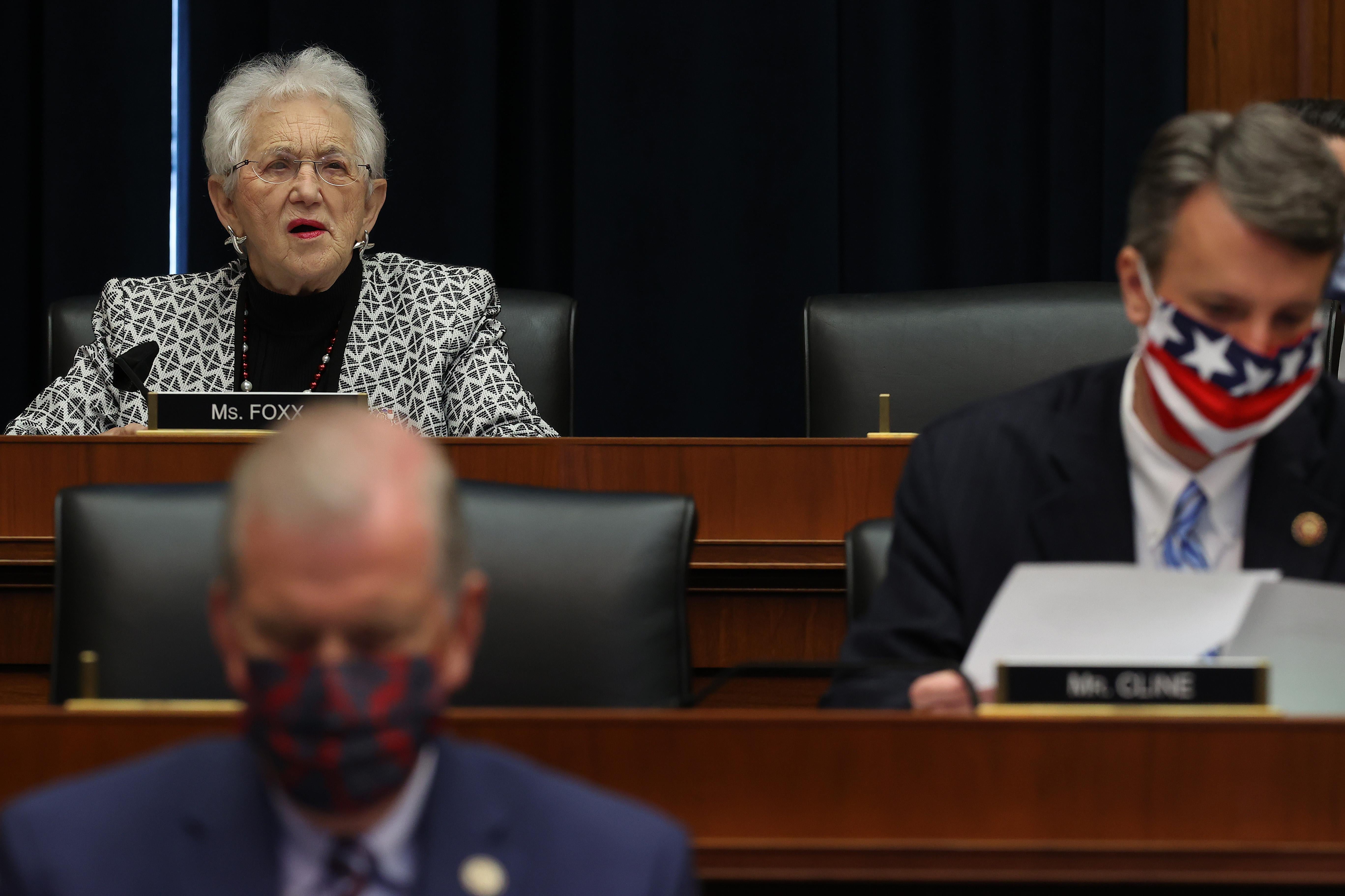 Three representatives seated in a hearing room, two wearing masks while Foxx does not