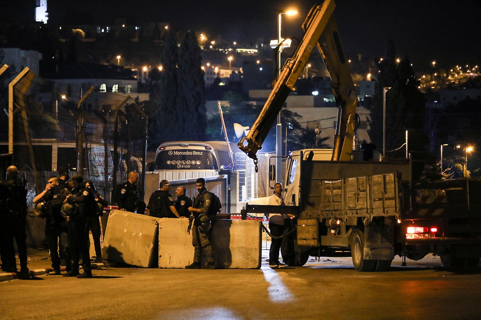 Israeli police stand around street barricades placed by a crane.