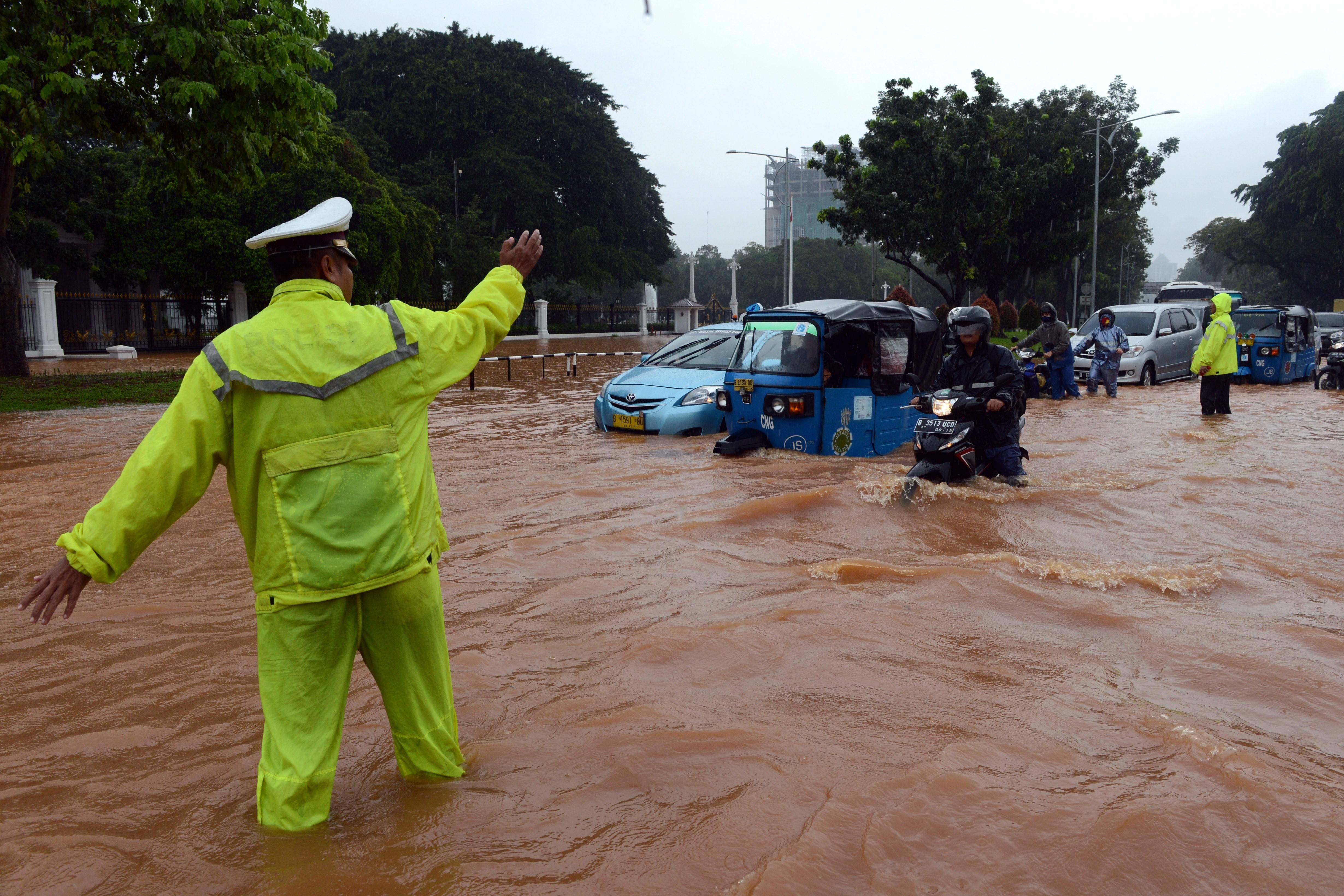 A policeman stands in floodwater as he directs traffic.