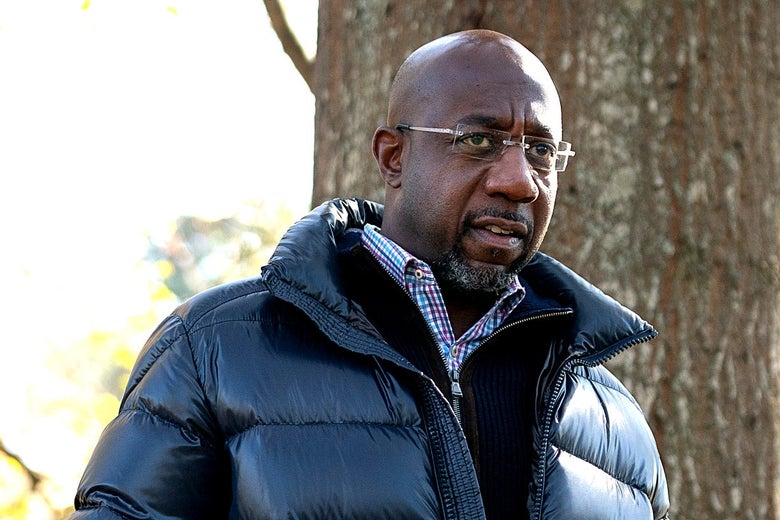 Raphael Warnock speaks at a campaign event in a black bubble coat.