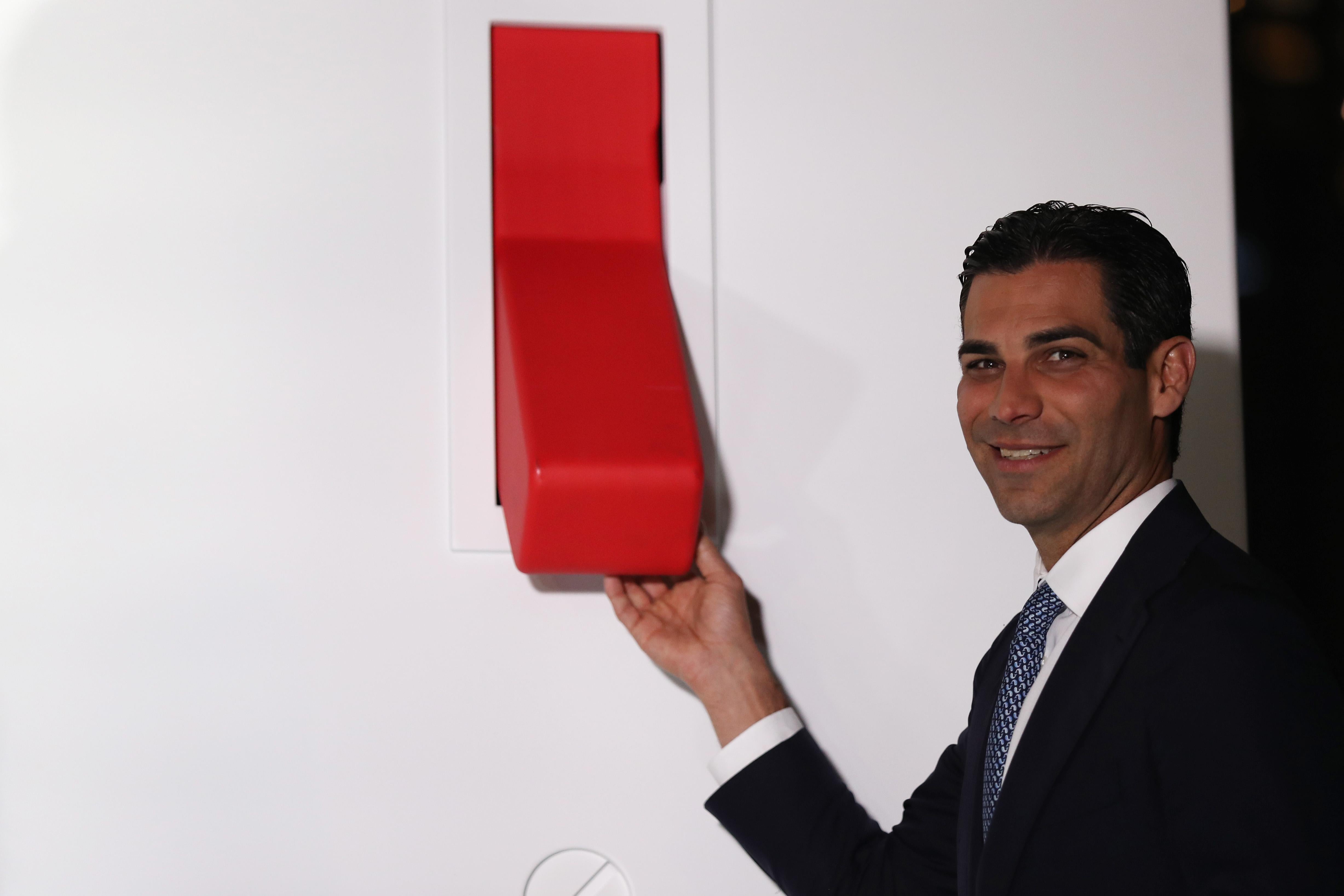 Francis Suarez poses in front of a giant red light switch on a wall at a new development in Miami