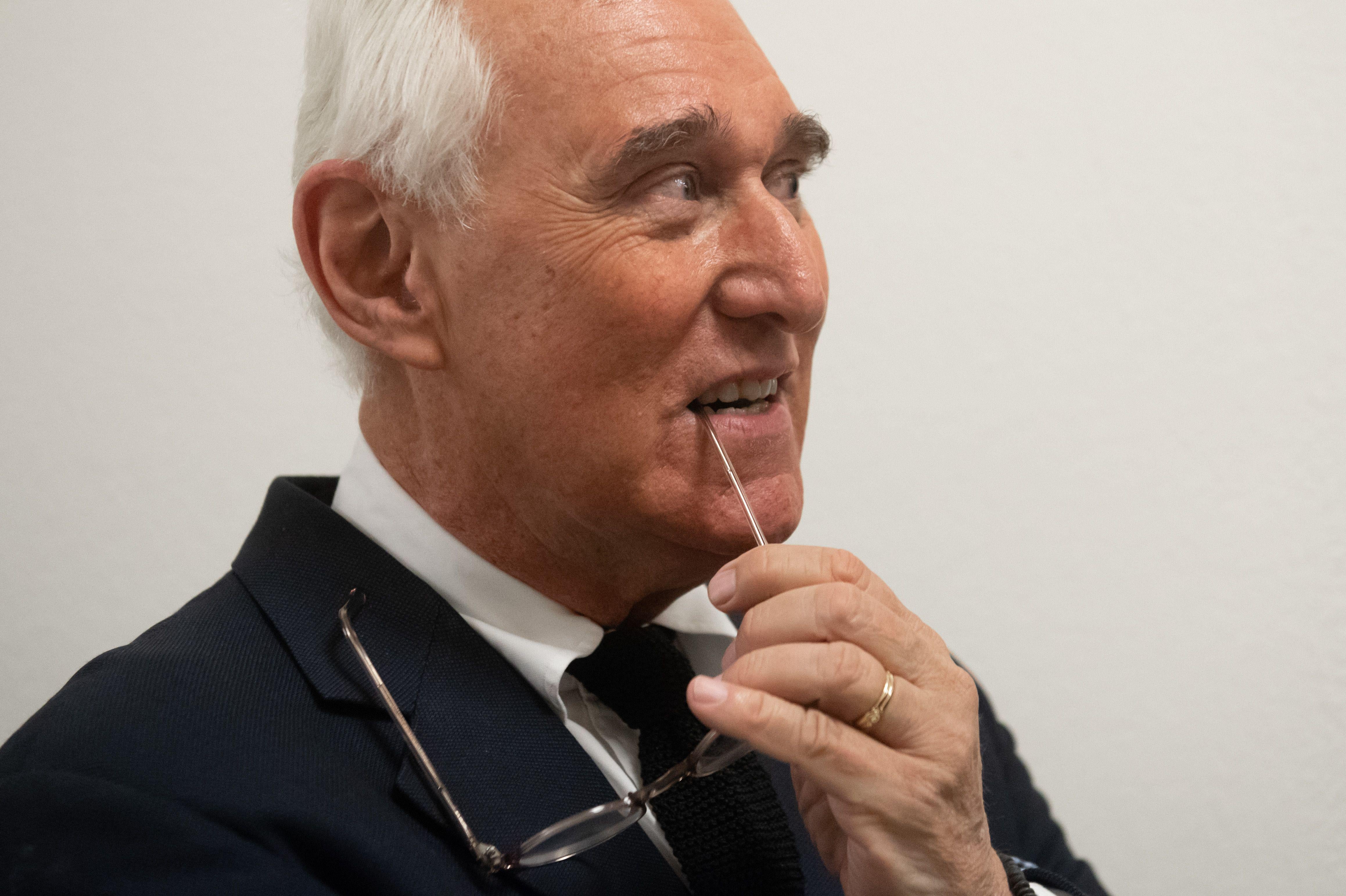 Roger Stone with a stem of his glasses in his mouth