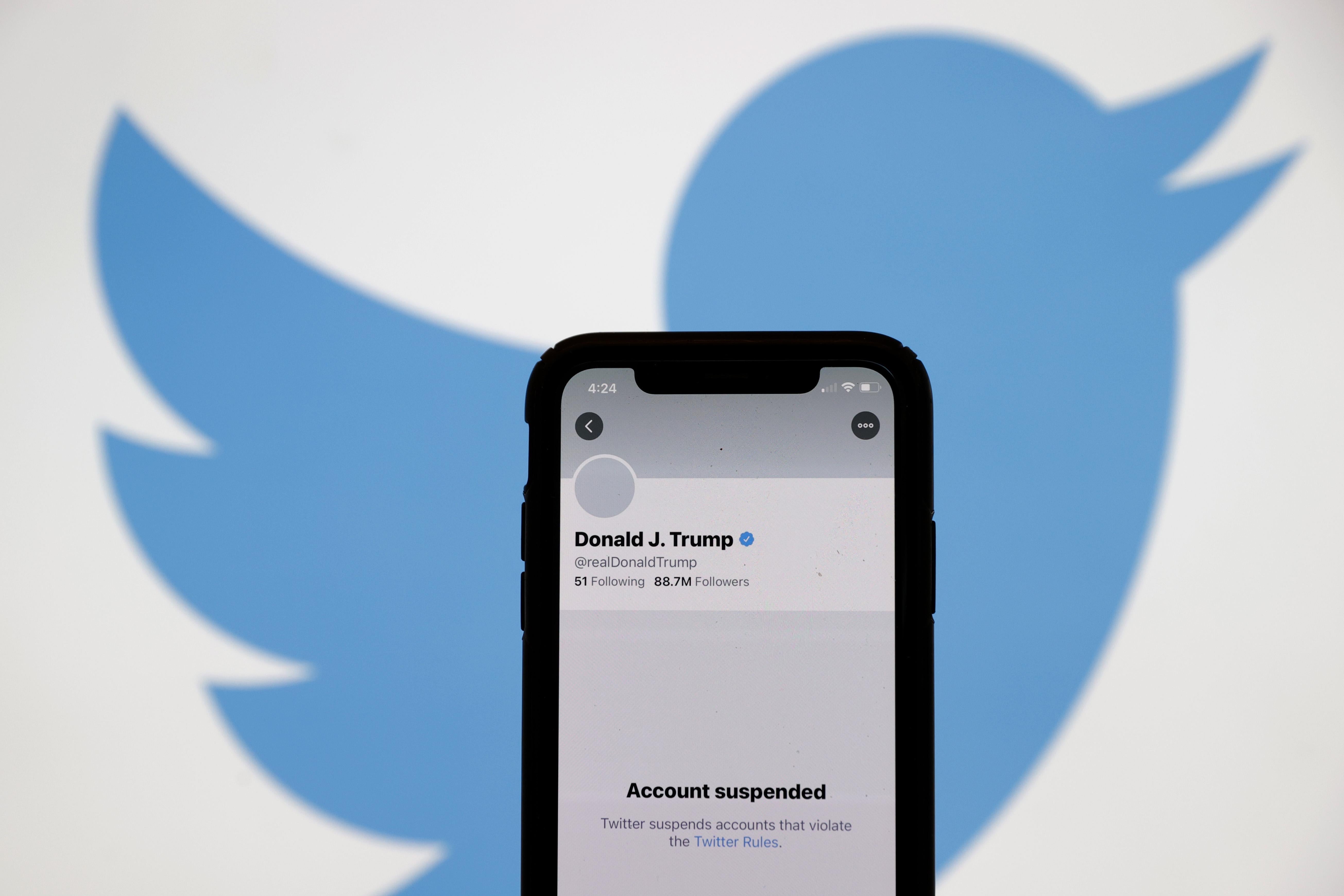 The suspended Twitter account of President Donald Trump on an iPhone screen, with the Twitter bird logo in the background
