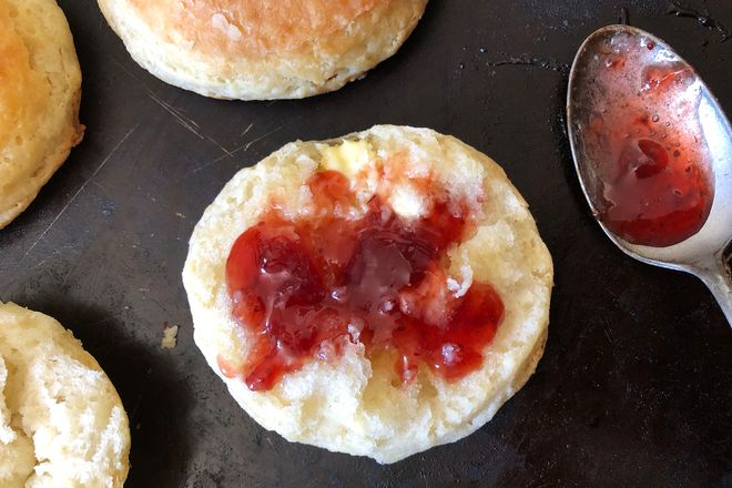 A halved biscuit covered in red jam.