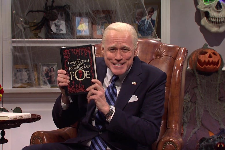 A still from SNL showing Jim Carrey, in costume as Joe Biden, sitting in a leather armchair holding up an Edgar Allen Poe anthology.