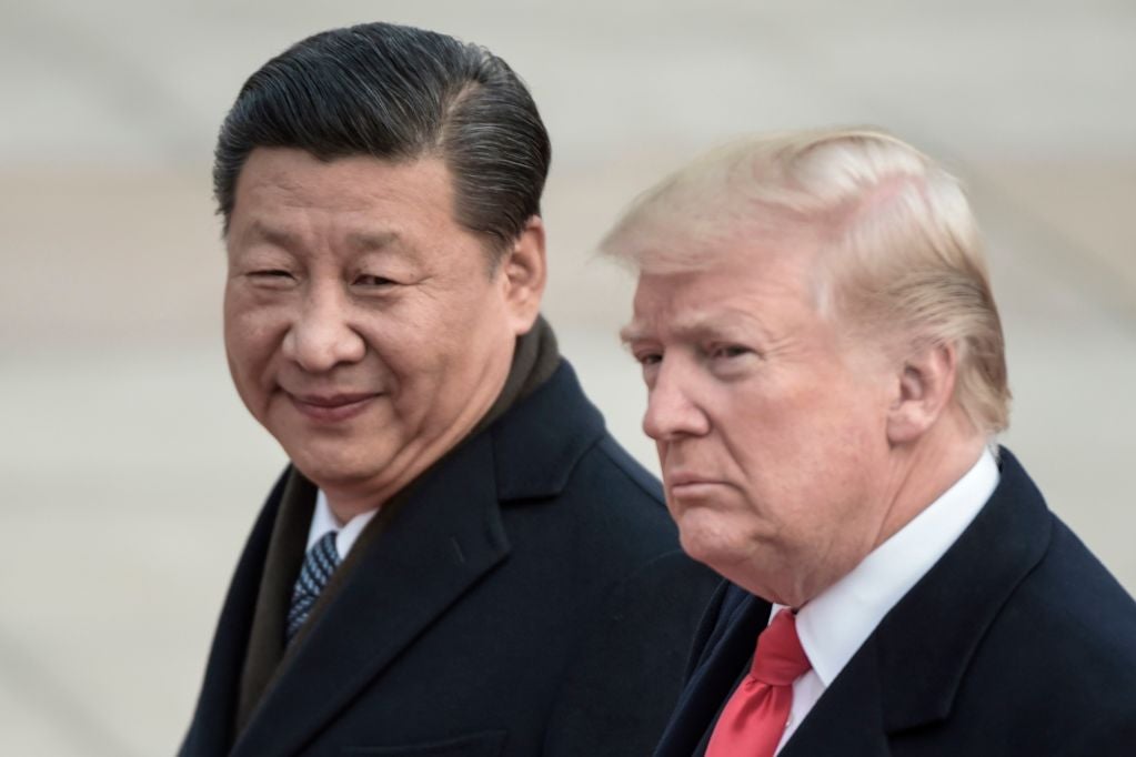 Xi looks at Trump with a smirklike expression while Trump looks into the distance.