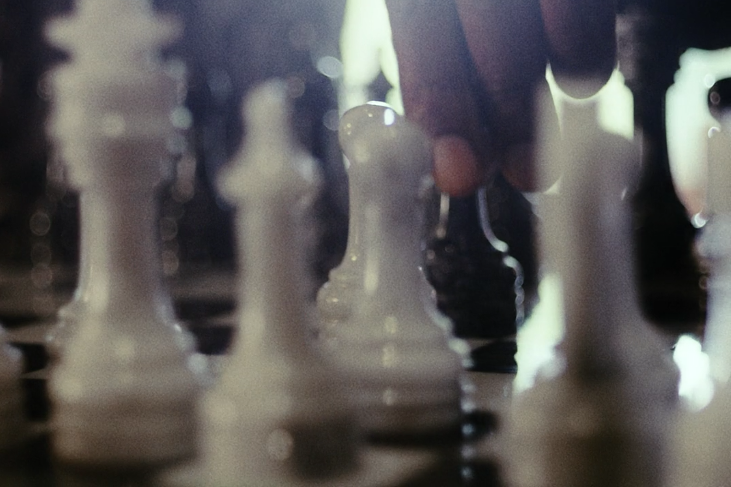 A hand is seen on a pawn in a chessboard.