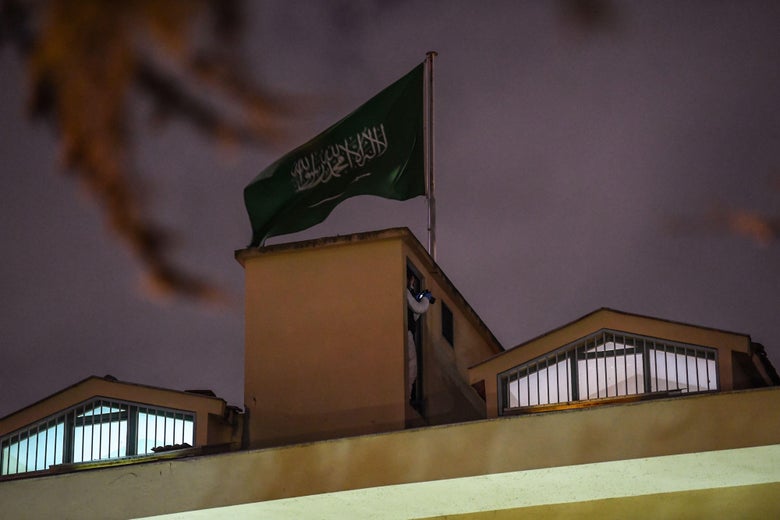 A Turkish investigator stands next to the Saudi flag on the roof of the Saudi consulate at night.