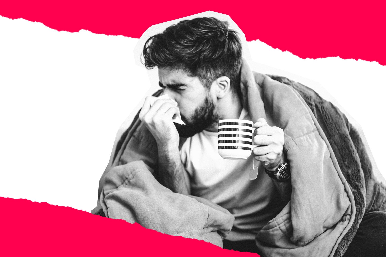 A sick man sniffling, with a blanket and a mug of tea