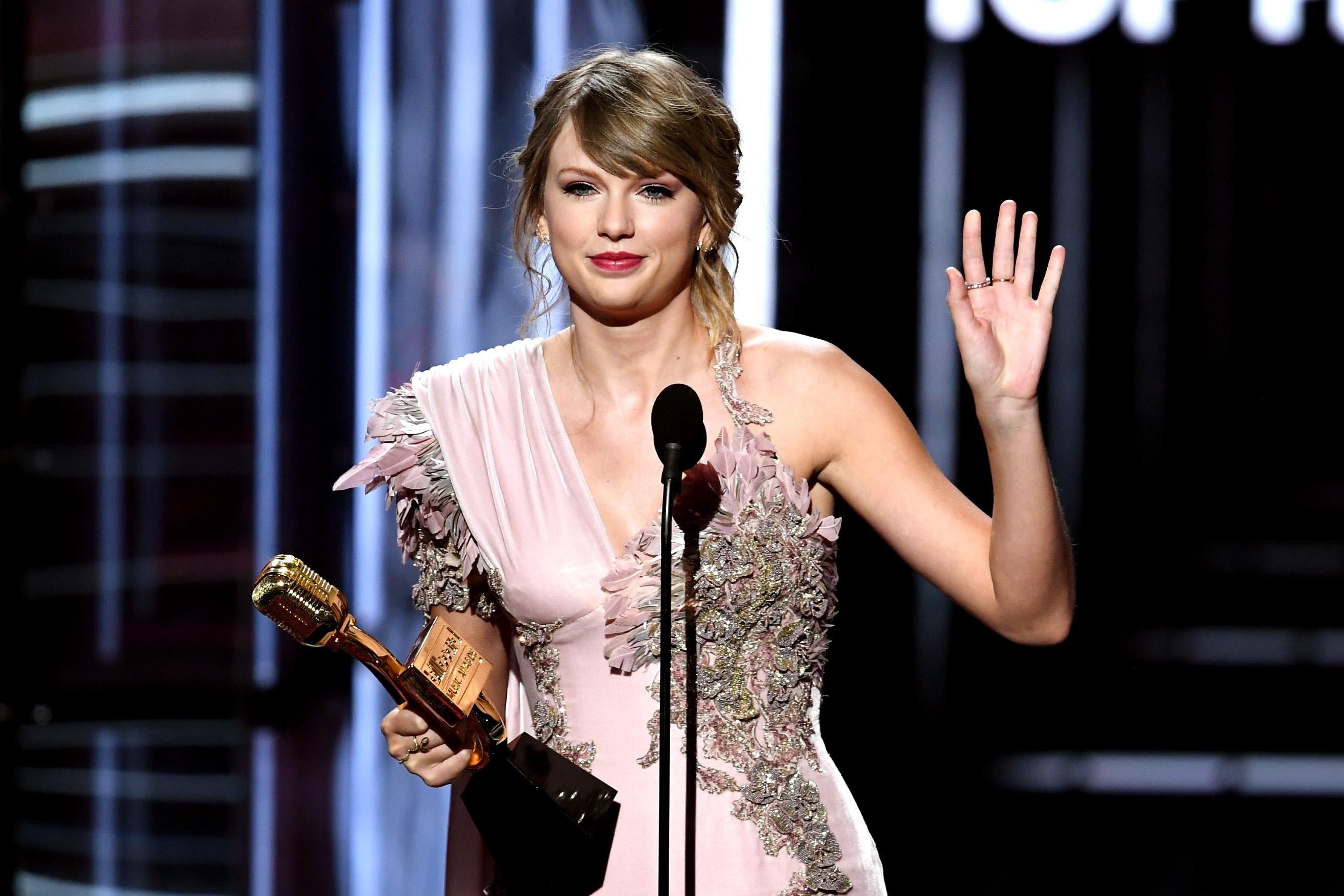 Taylor Swift waving goodbye at an awards show.