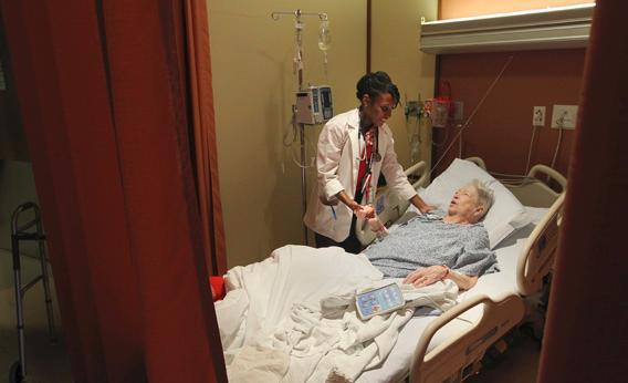 Boston University Medical student Erica Perry, left, checks on patient Alma Conroy at the Boston Medical Center.
