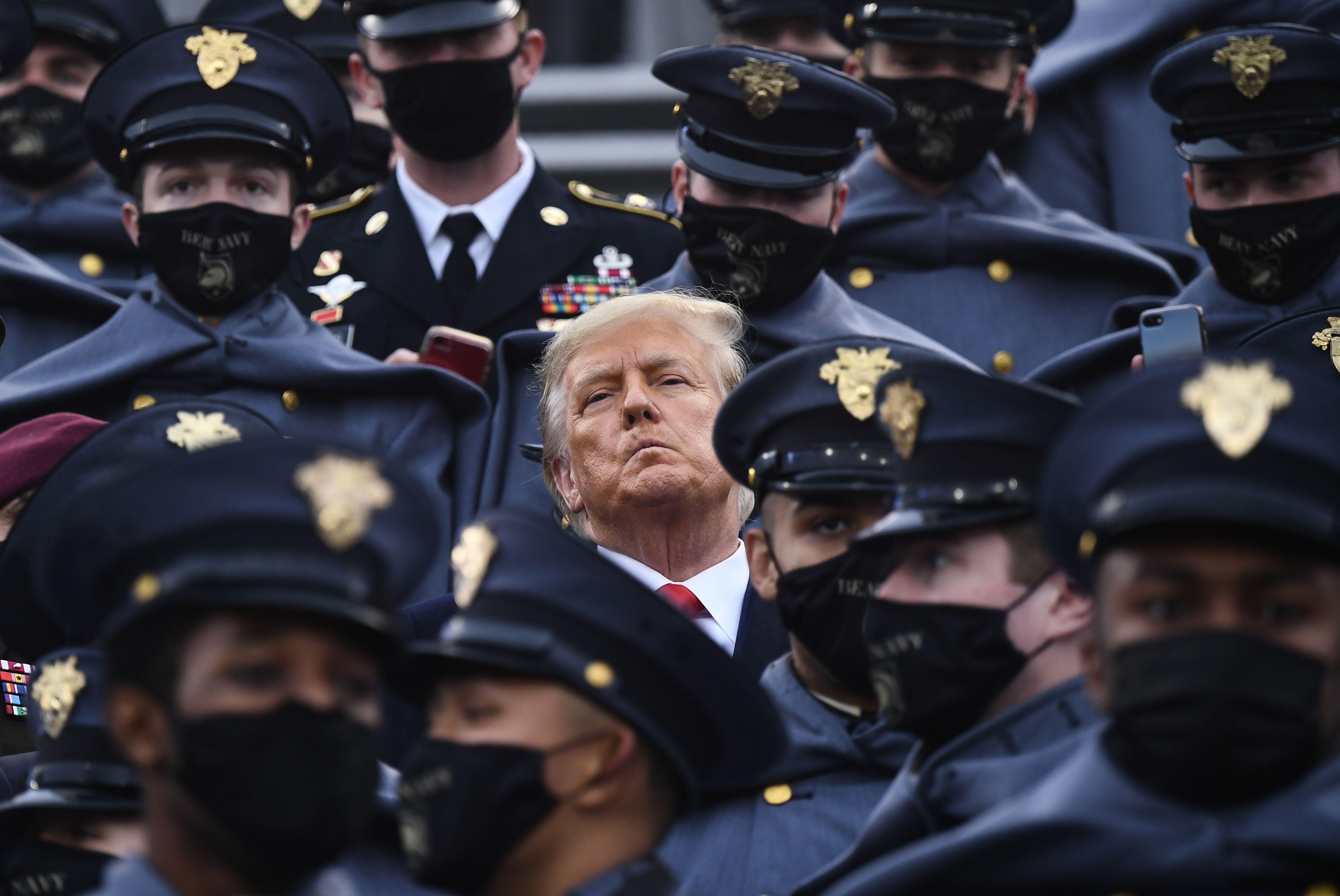 Trump with his mask off scowling in a sea of masked cadets.