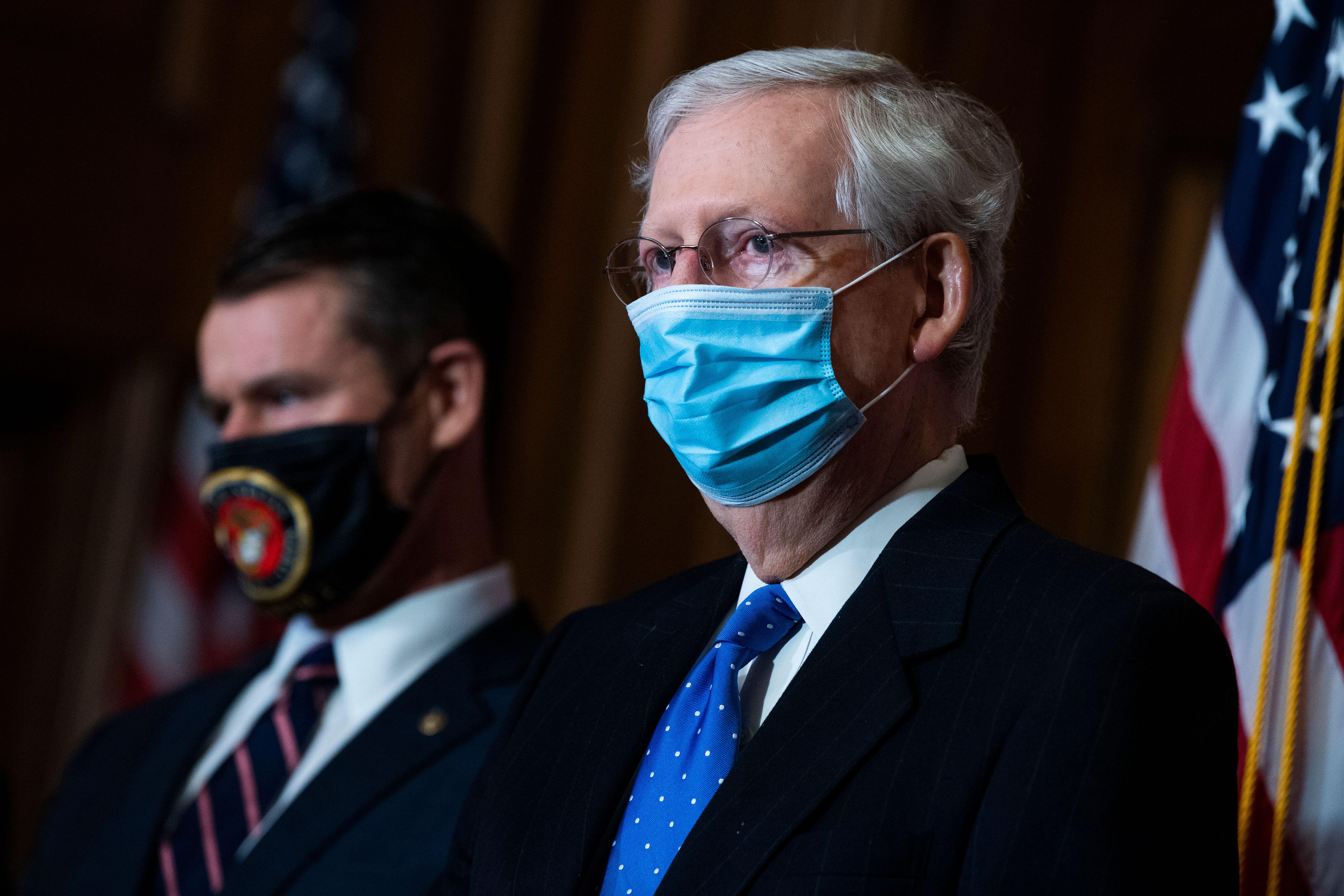 Mitch McConnell in a mask with a masked male colleague standing next to him.