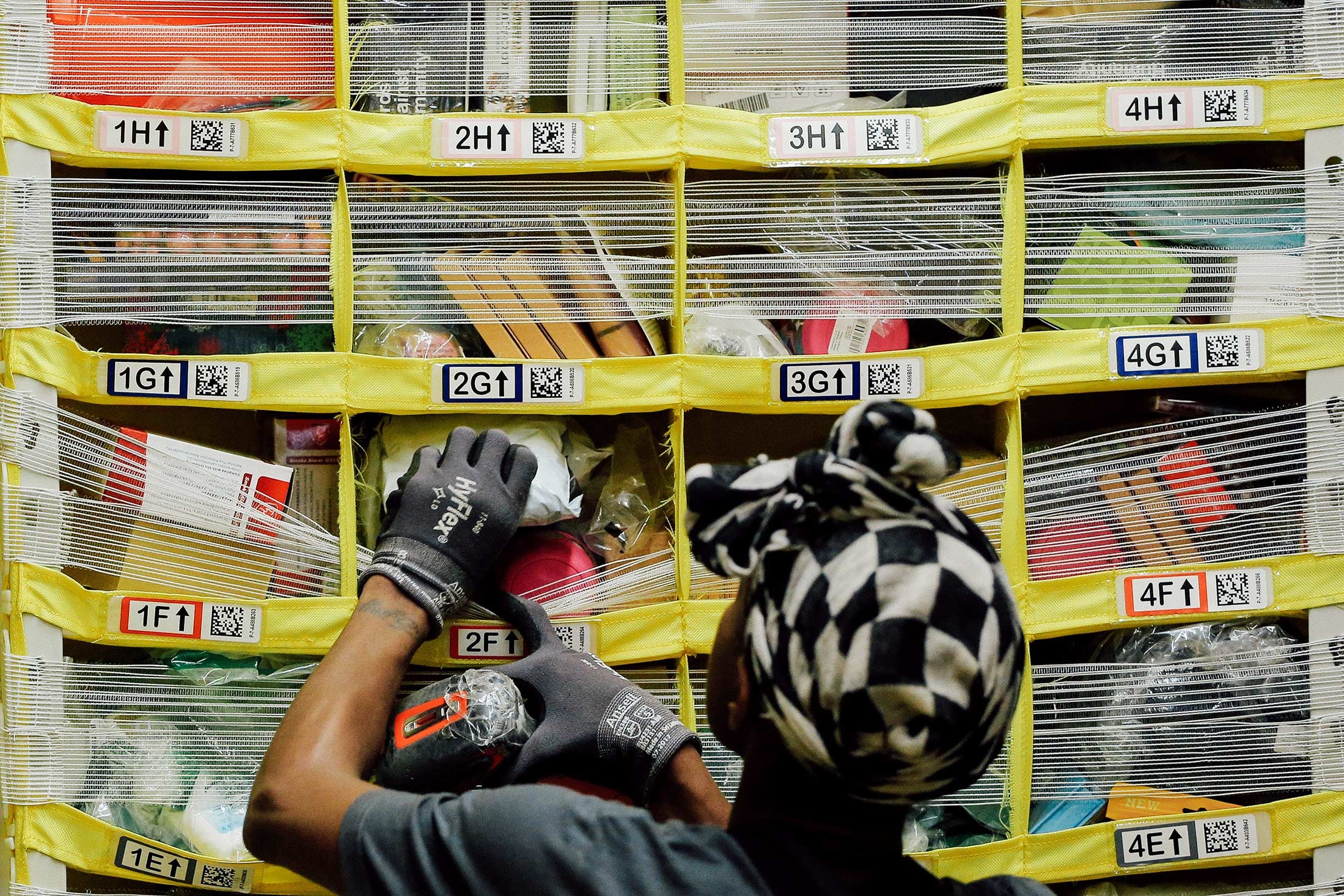A worker sorts products into bins inside an Amazon Fulfillment Center.