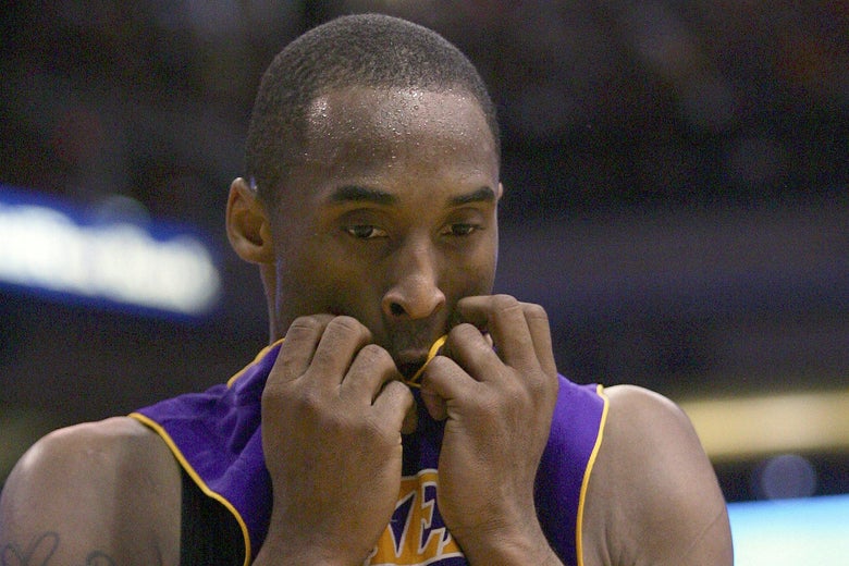 Kobe Bryant pulling his jersey into his mouth and looking down.