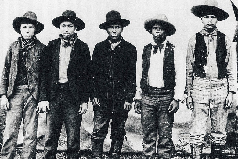 Five boys are lined up, hands by their sides, chained. 