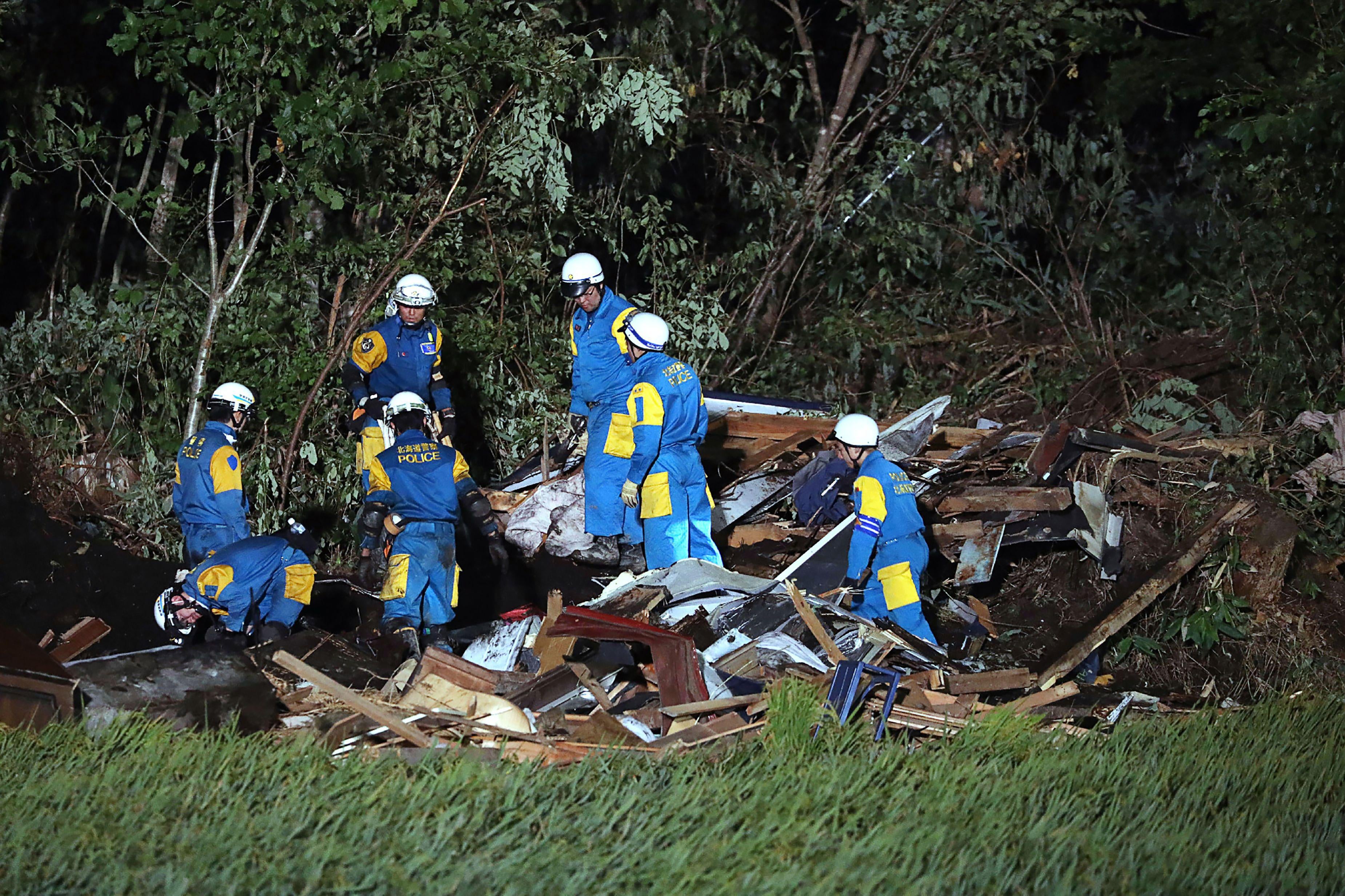 Japanese policemen work during a rescue operation in the area affected by landslides triggered by the earthquake. 