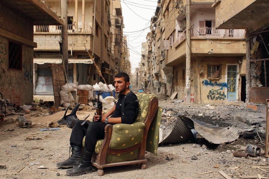 A member of the Free Syrian Army holds his weapon as he sits on a sofa in the middle of a street in Deir al-Zor on April 2, 2013.