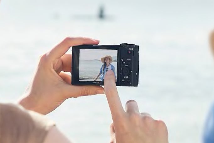 Finger pointing at a figure on a camera screen.