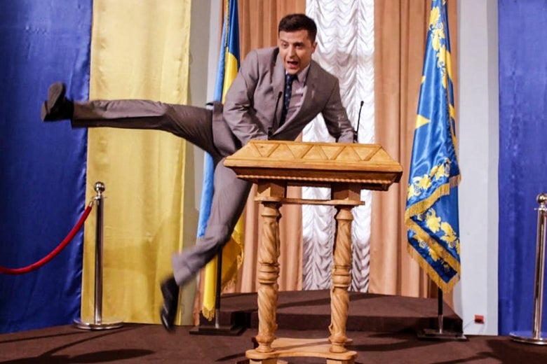 Zelensky in character leg-kicking at a presidential podium.
