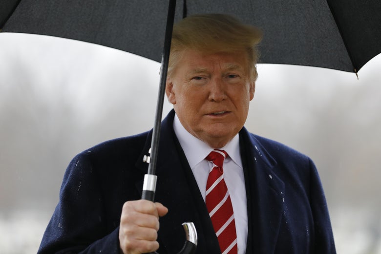 President Trump stares directly at the camera while holding an umbrella.