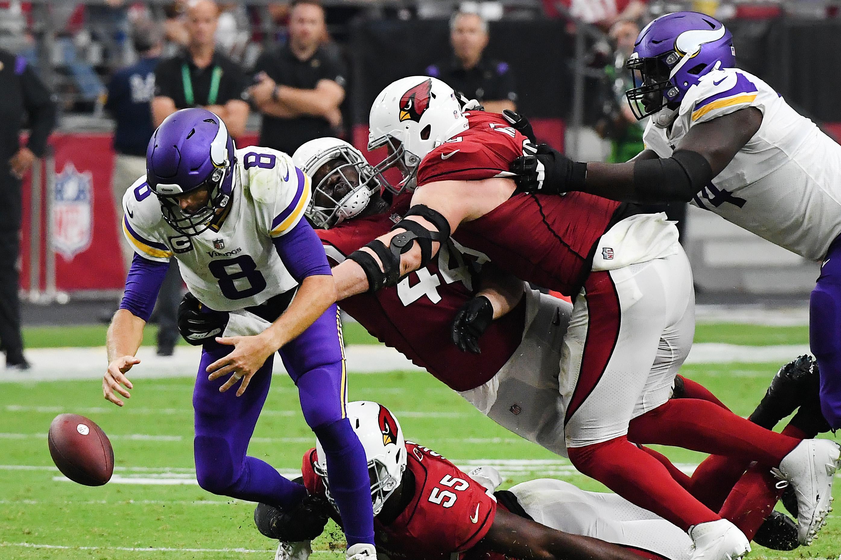 Cousins staring at the football on the ground that's been knocked out of his hands as three giant Cardinals envelop him.