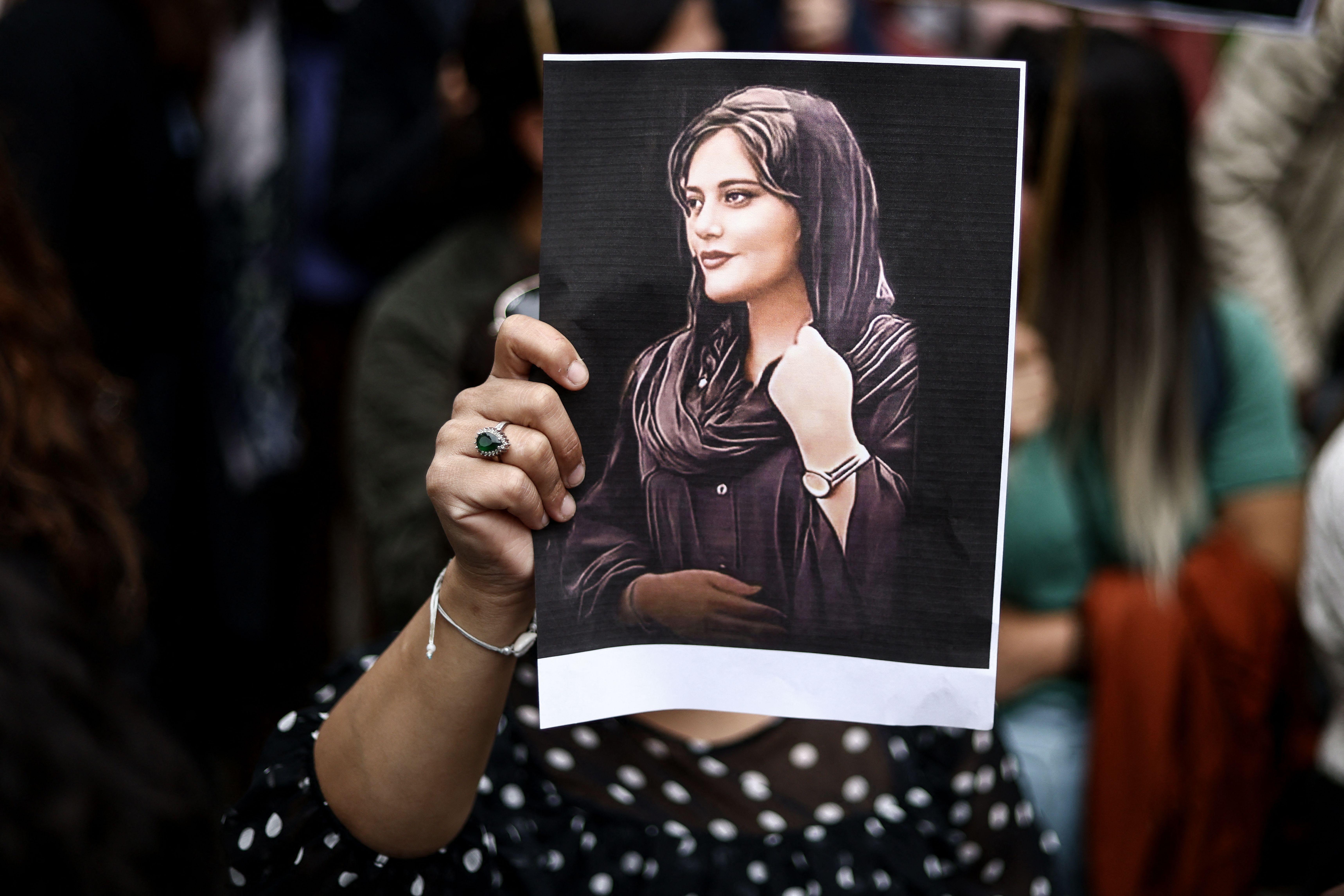 A woman holding a photo of Mahsa Amini