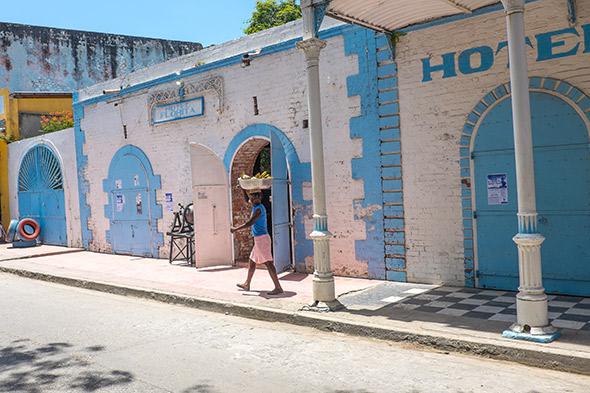 A woman carries a basket of bananas on her head outside the Hotel Florita in Jacmel, May 5, 2014.